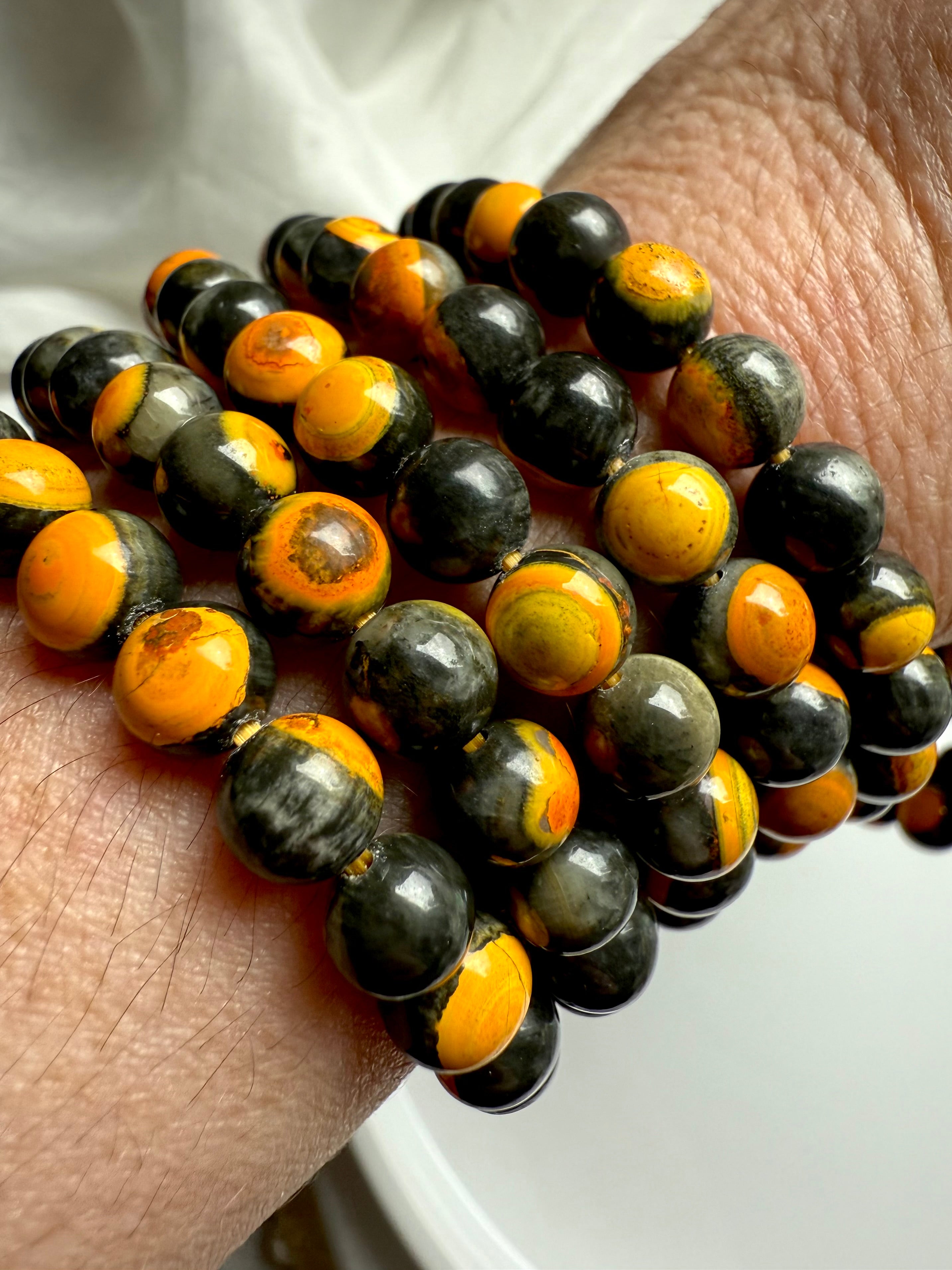 Close-up of bumblebee jasper beads showcasing swirls of yellow, charcoal, and orange — energizing stone for joy, confidence, and clarity