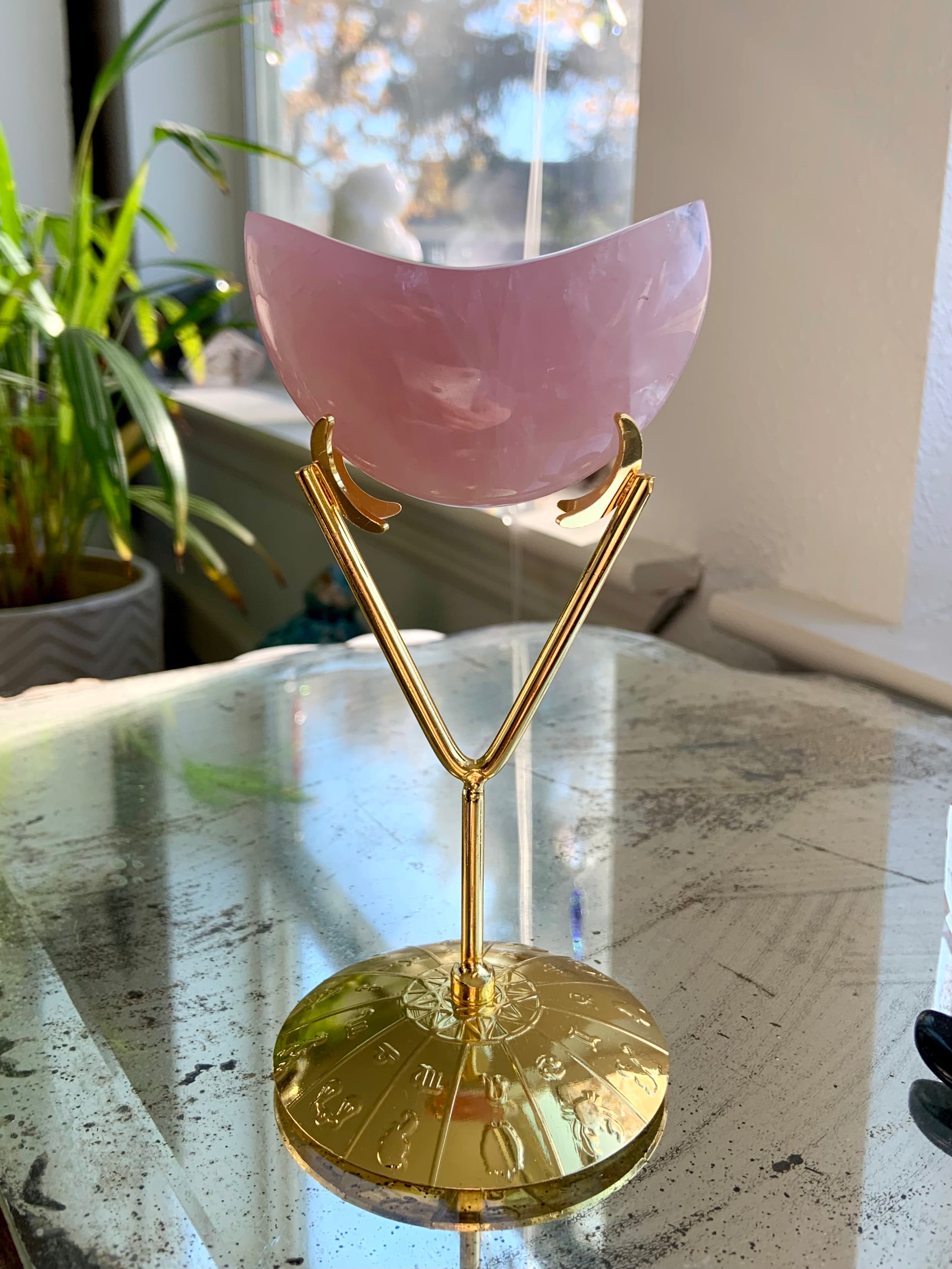 Crystal holder with zodiac design displaying a Rose Quartz moon — shown on a mirror surface, ideal for elegant crystal decor.
