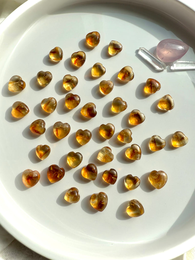 Mini Citrine Crystal Hearts shown on a white plate, photographed in natural light