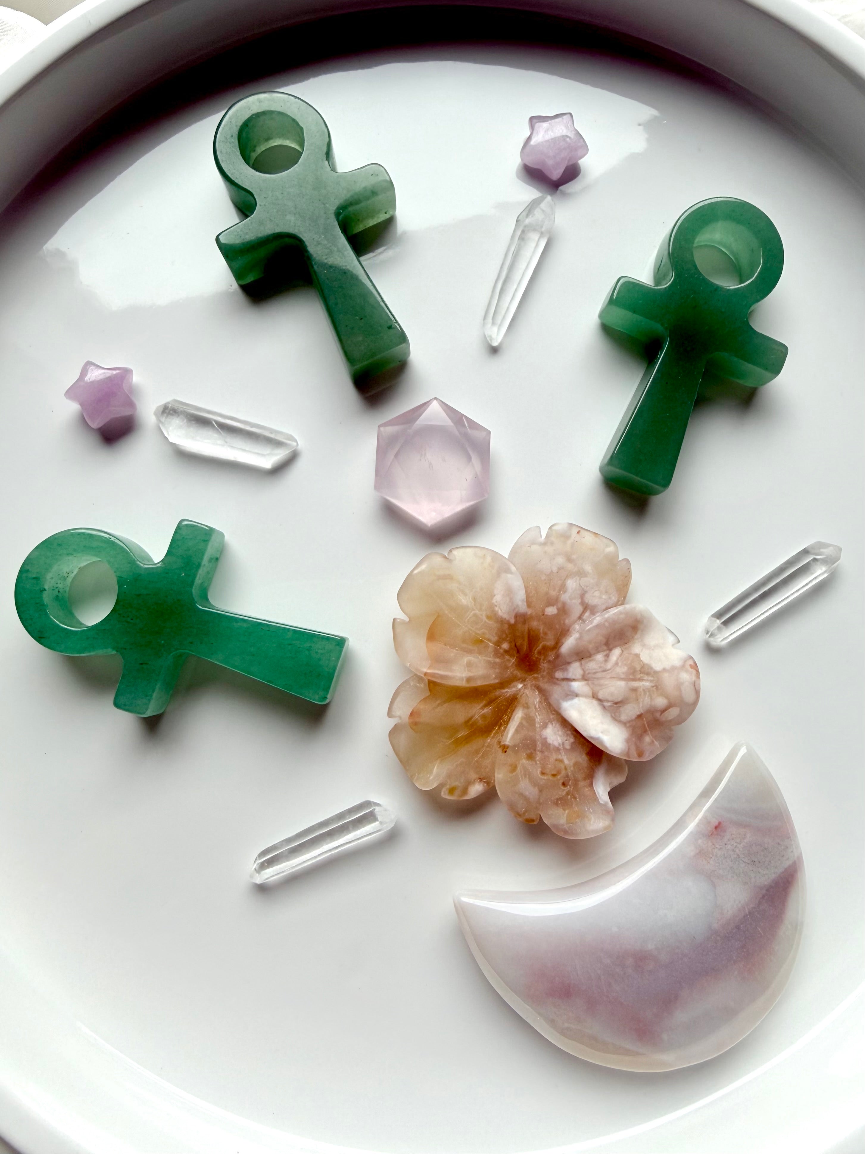 Green Aventurine ankh carvings arranged on white tray with rose quartz, clear quartz points, and flower crystal – life force symbol for heart healing and altar work