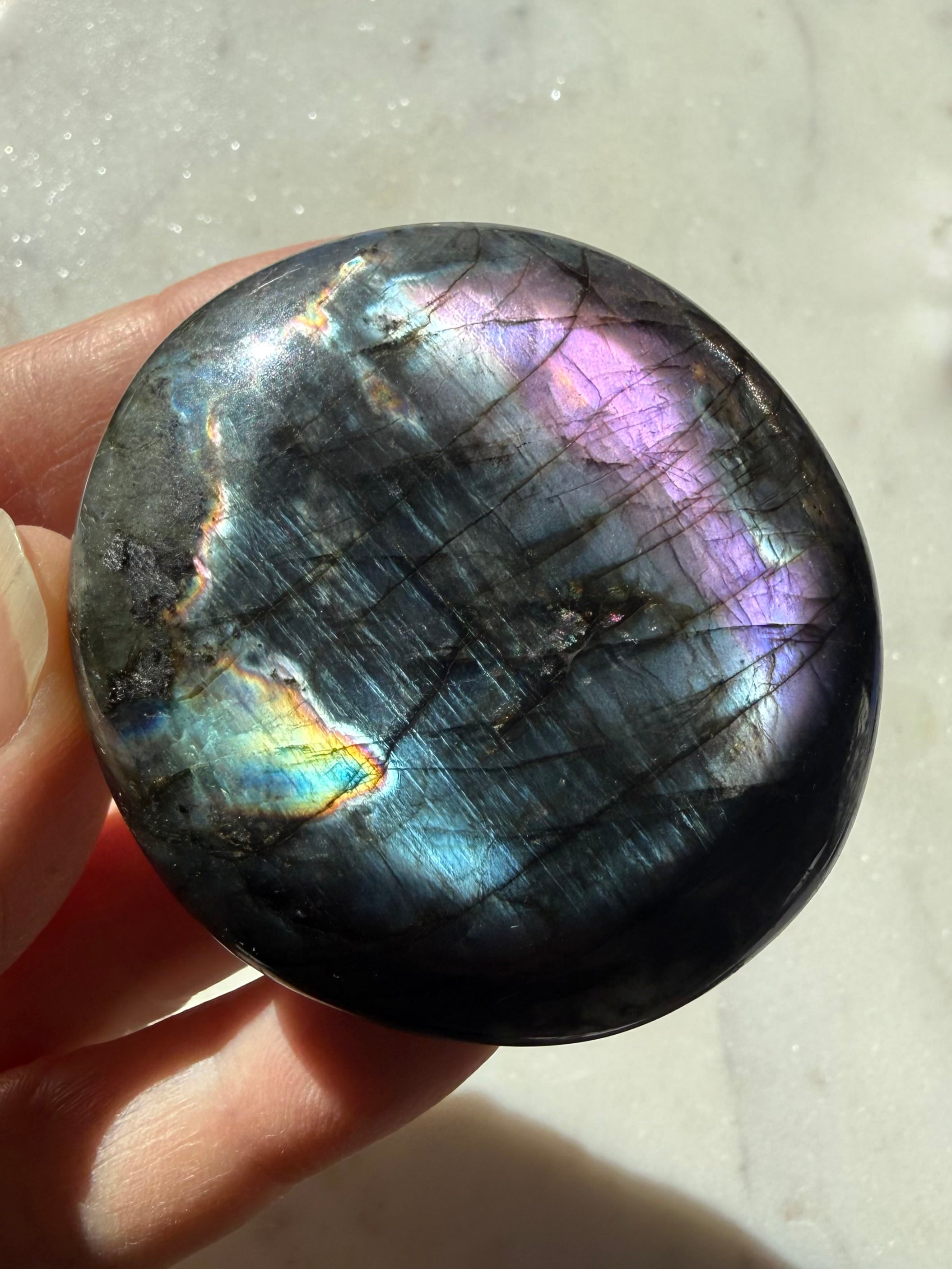 Labradorite palm stone showing blue, green, purple and silvery rainbow flash in directional light