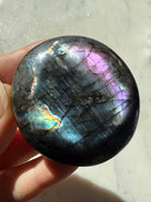 Labradorite palm stone showing blue, green, purple and silvery rainbow flash in directional light