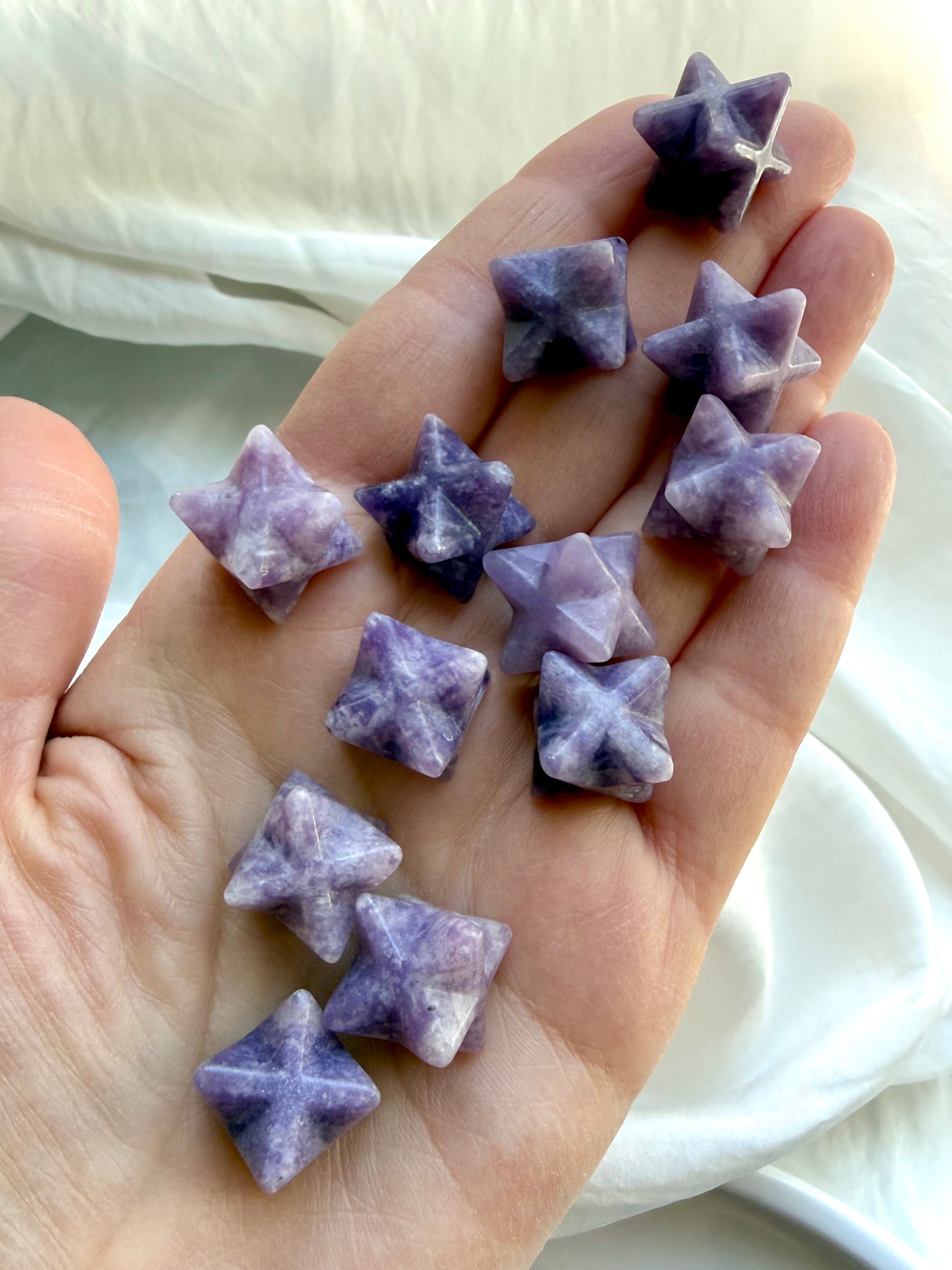 handful of mini lepidolite stars in palm, soothing purple crystals for anxiety relief and emotional grounding
