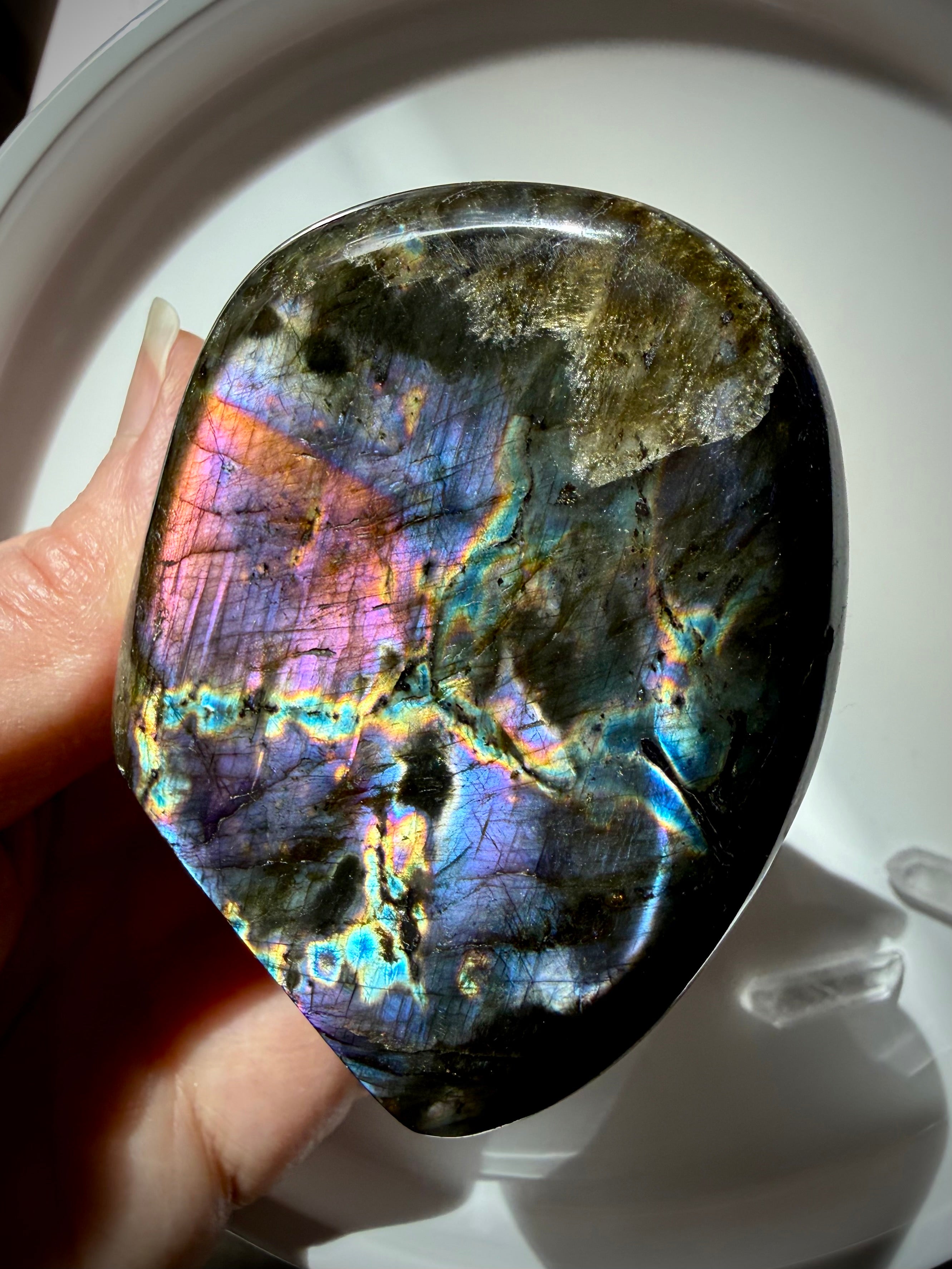 Rainbow Labradorite crystal freeform held in hand showing vivid pink, purple, blue and gold flash