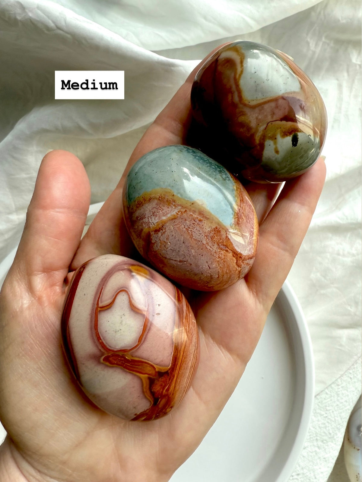 Medium Polychrome Jasper palm stones displayed in hand, showing size, shape, & vibrant earthy colors