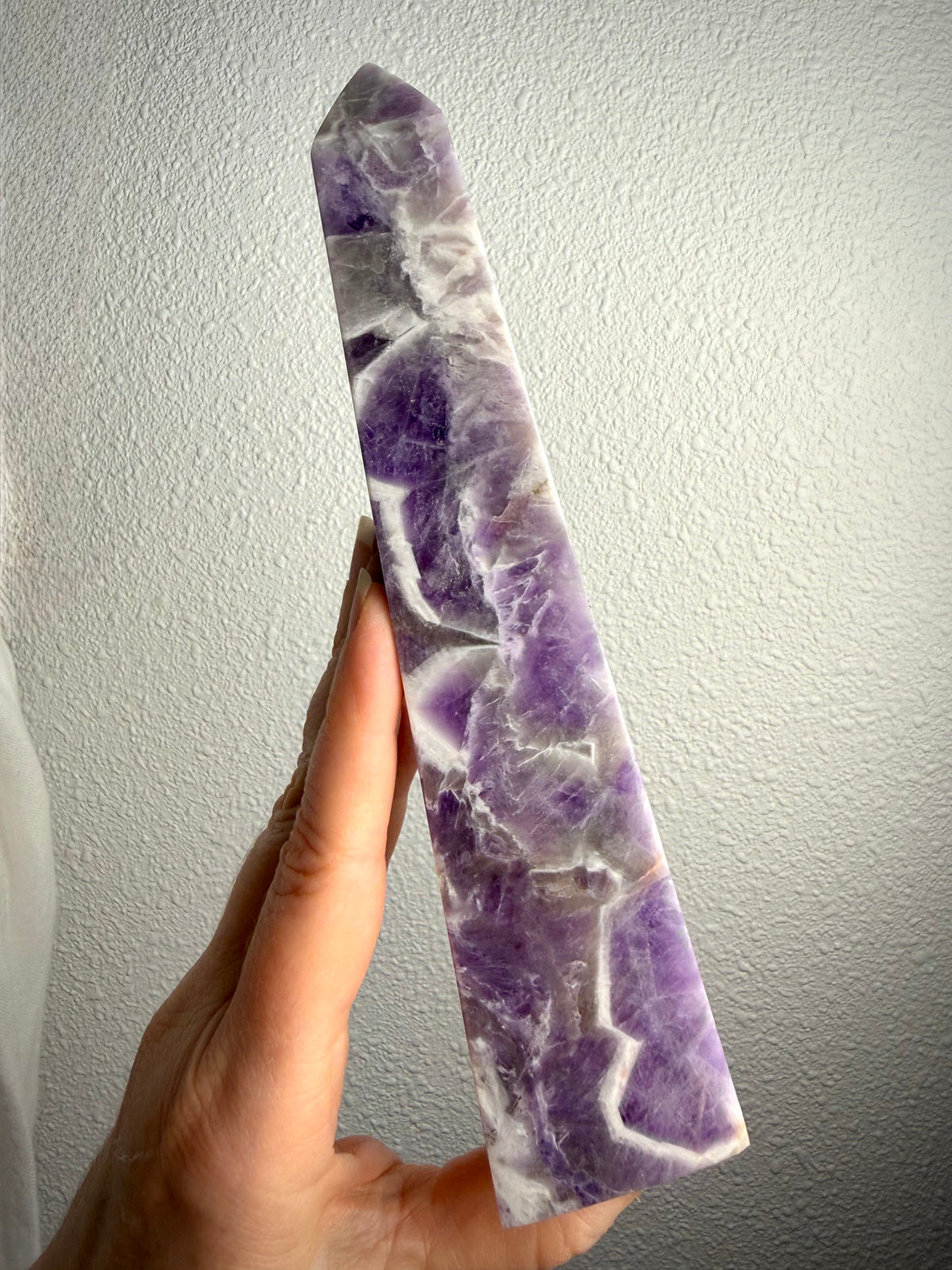 Tall Dream Amethyst crystal point showing its slender shape, rich purple coloring and distinctive zigzag quartz patterns