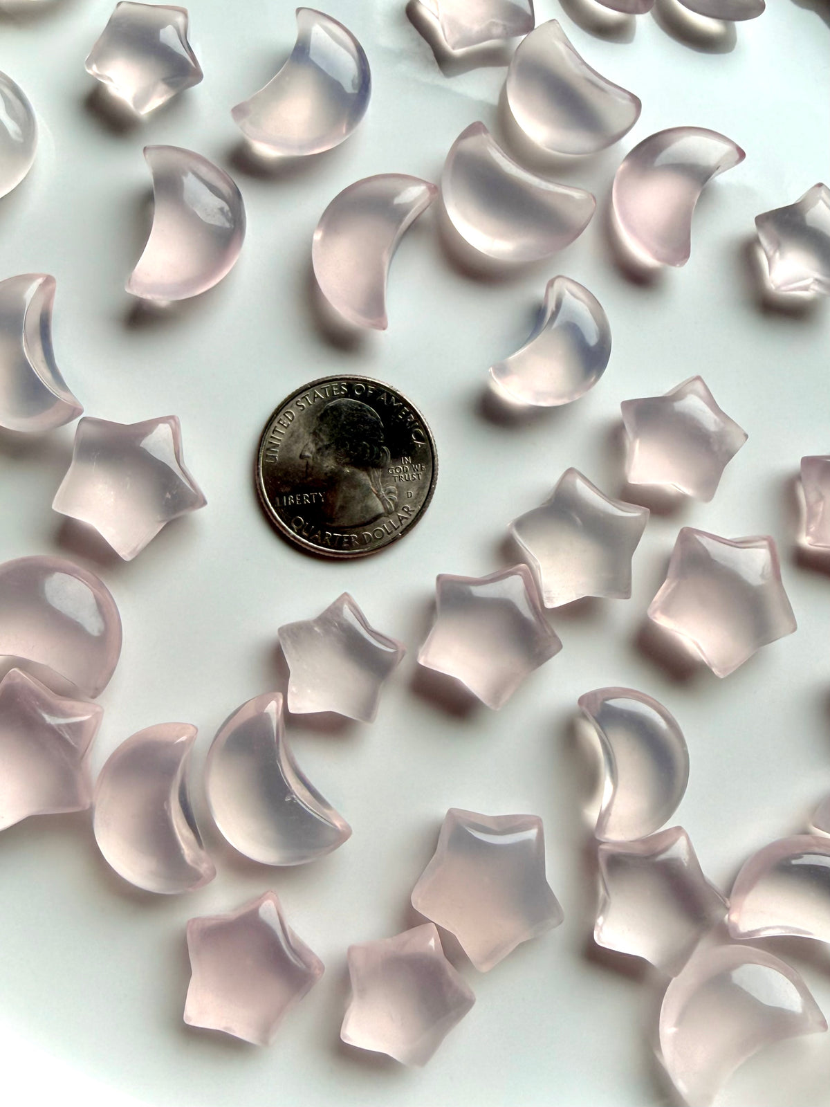 Rose Quartz crystal moons and stars with luminous blush pink color shown with a US quarter for scale