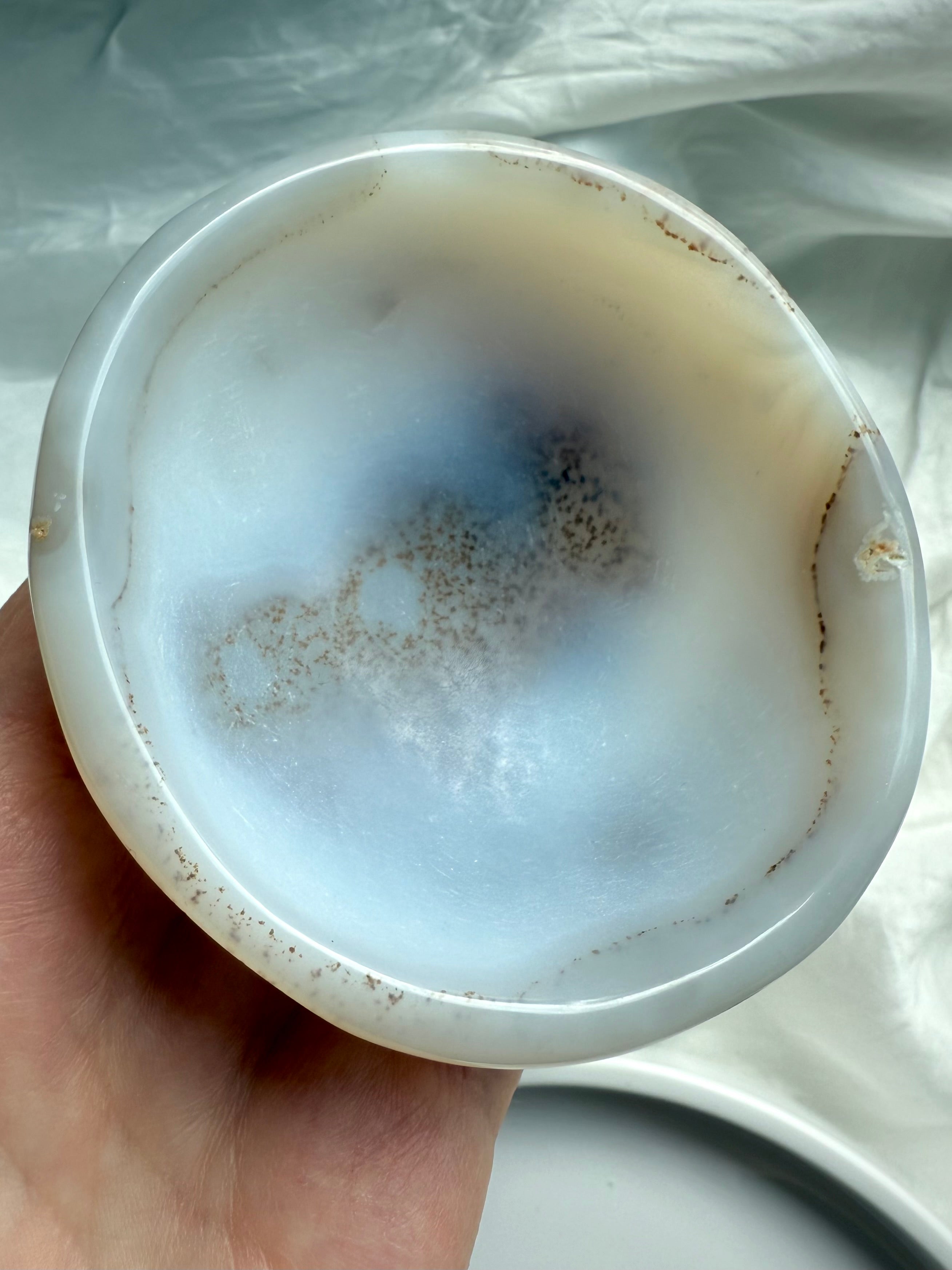 Hand holding White Agate bowl showing inner cloudy patterns and crystal inclusions, healing altar tool for serenity and balance