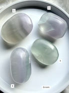 yttrium fluorite palm stones flat lay on white surface front view, options 1-4 with pastel green and lilac hues for clarity and emotional balance