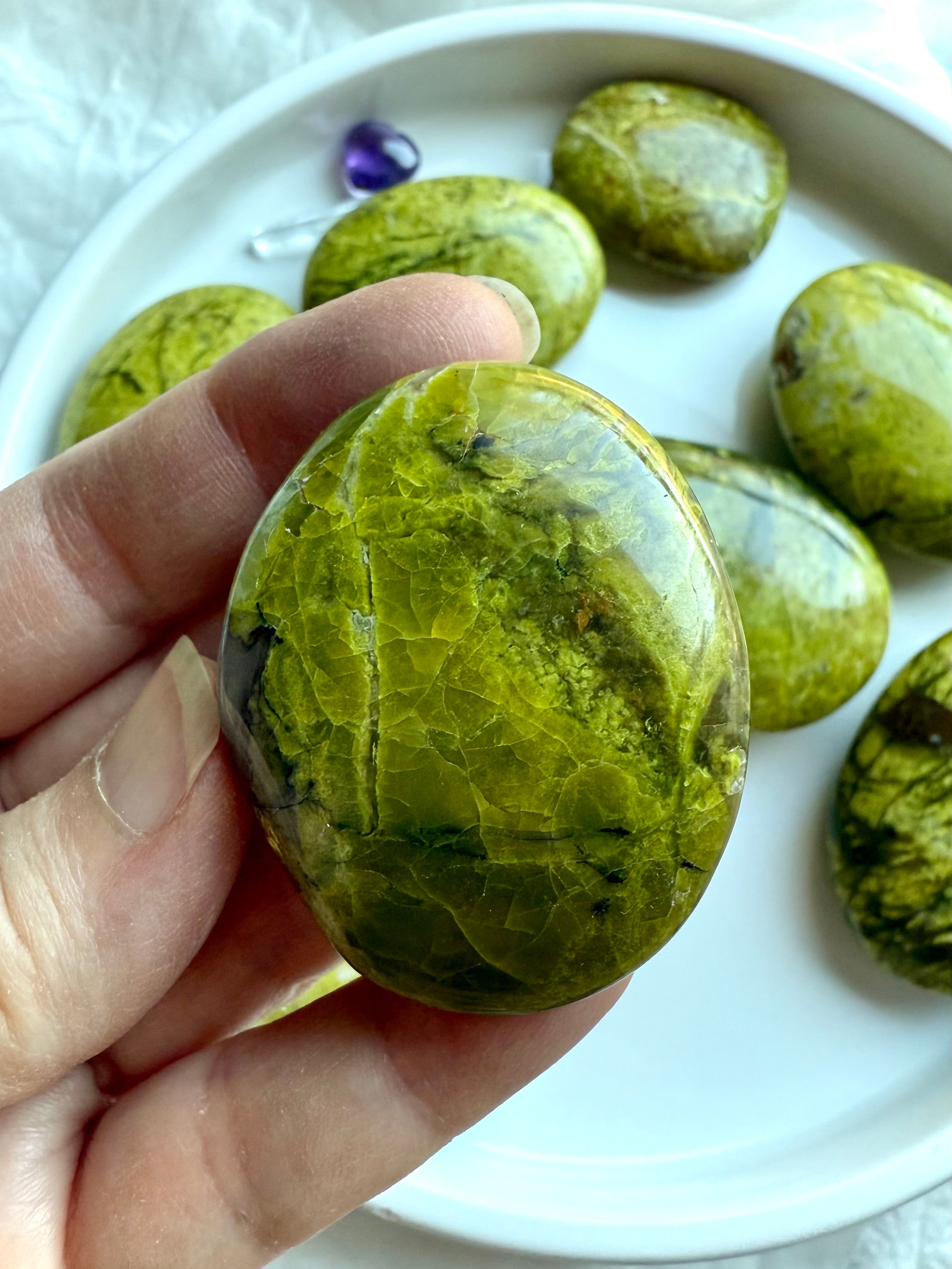 Detailed shot of a Green Opal palm with golden, green, and earthy mineral veining — unique healing stone for emotional support.