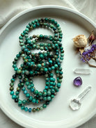  Natural Chrysocolla Shattuckite gemstone bracelets in a pile with vibrant blue-green tones, shown with clear quartz and amethyst crystals