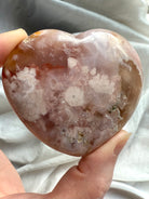 Polished flower agate crystal heart held in hand for heart chakra healing and meditation