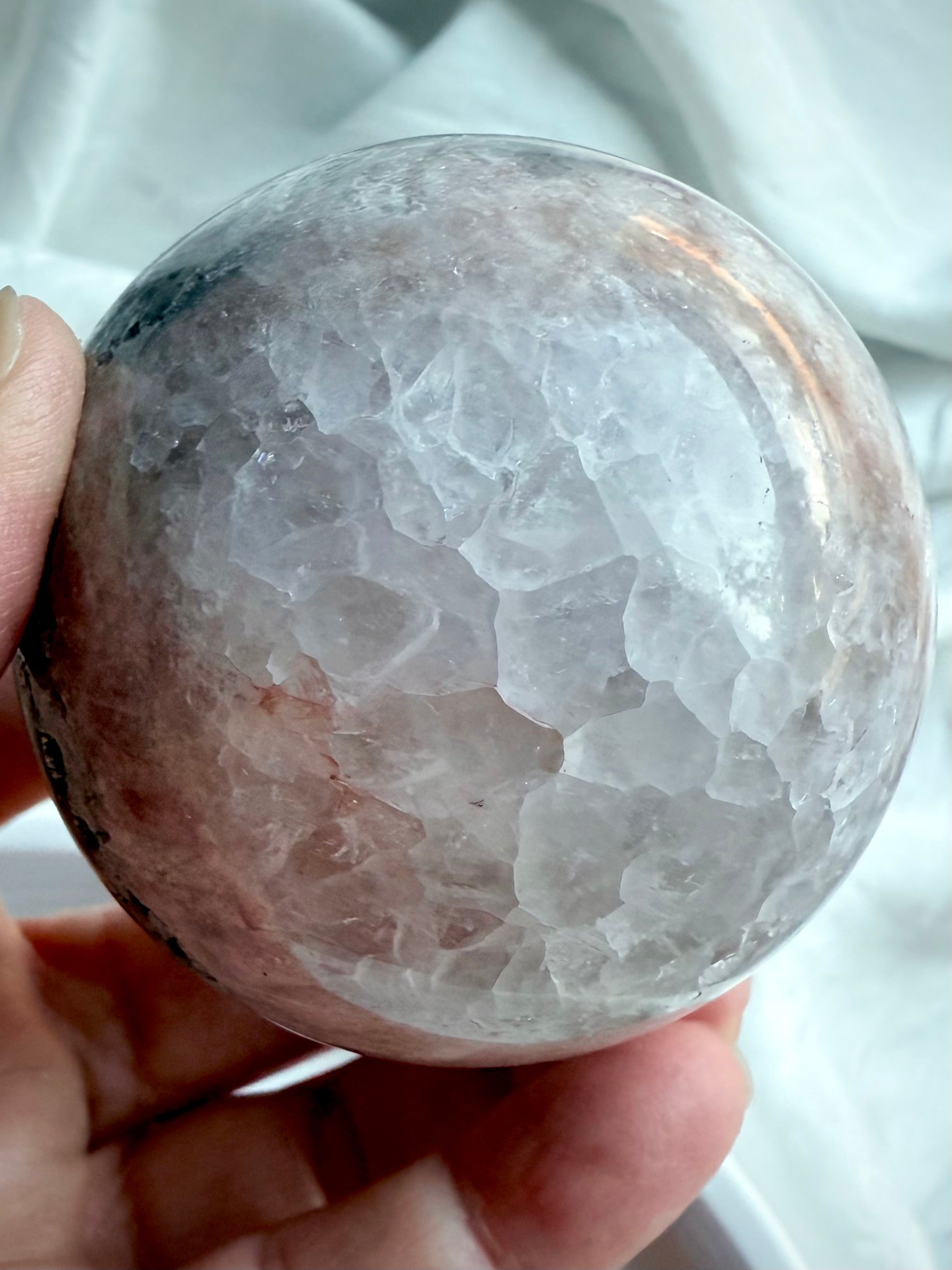 Close-up of agate sphere showcasing polished quartz crystal texture with soft gray and smoky tones, natural light