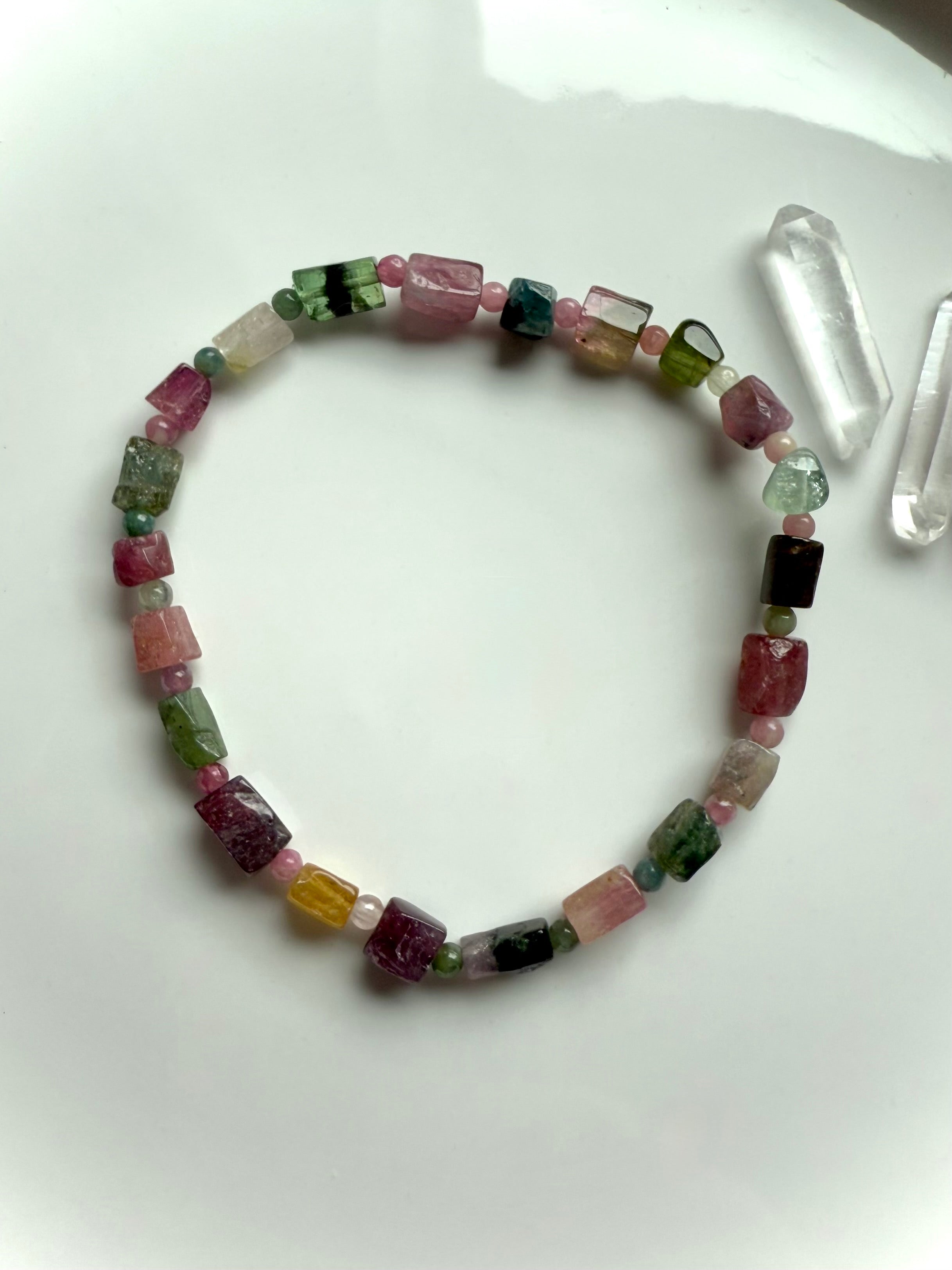 Our Rainbow Tourmaline Bracelet made with irregular cube shaped gems shown on a white plate