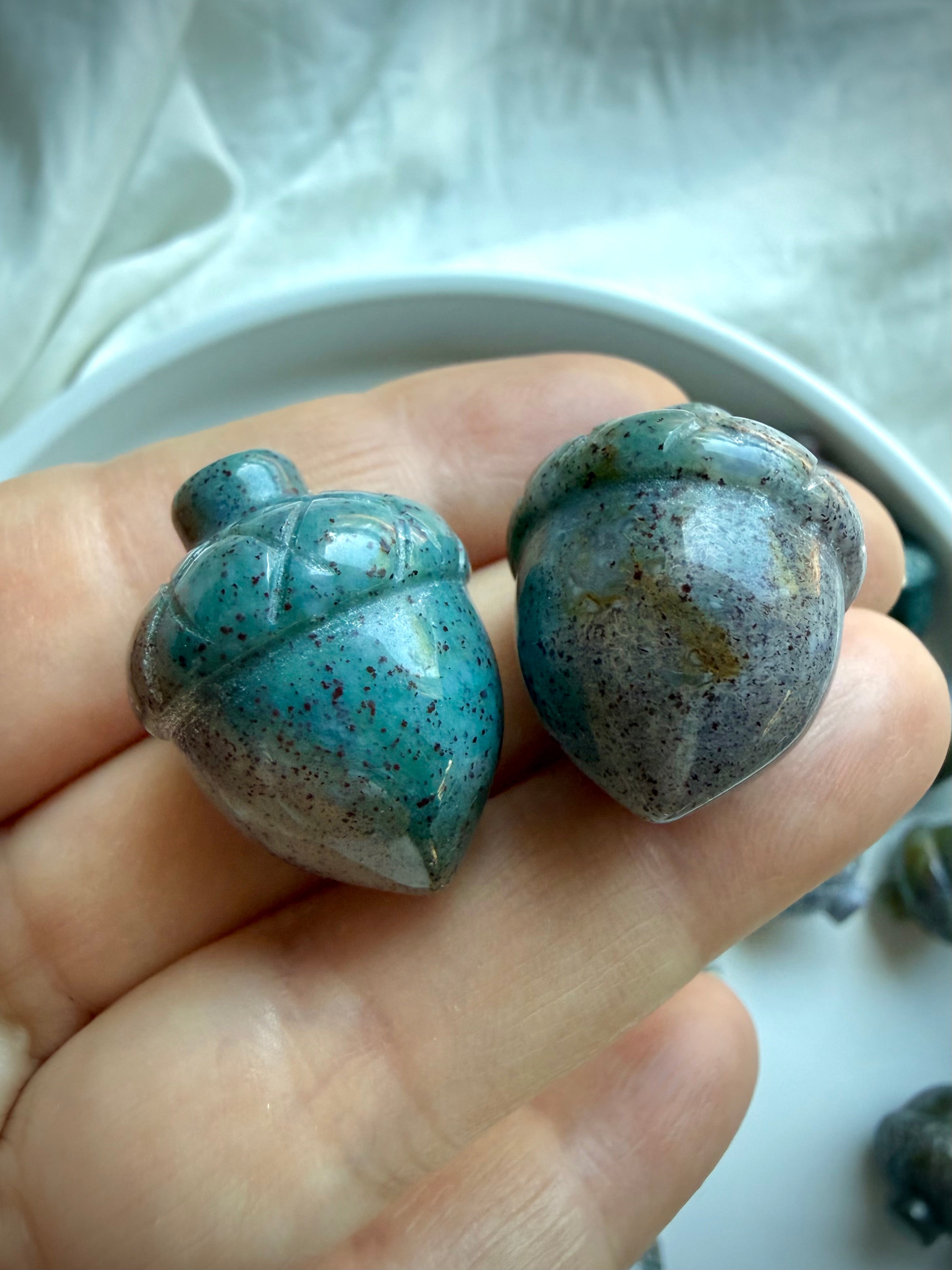 Mini Ocean Jasper acorn carvings held in hand showing petite size, teal color and natural speckled patterns