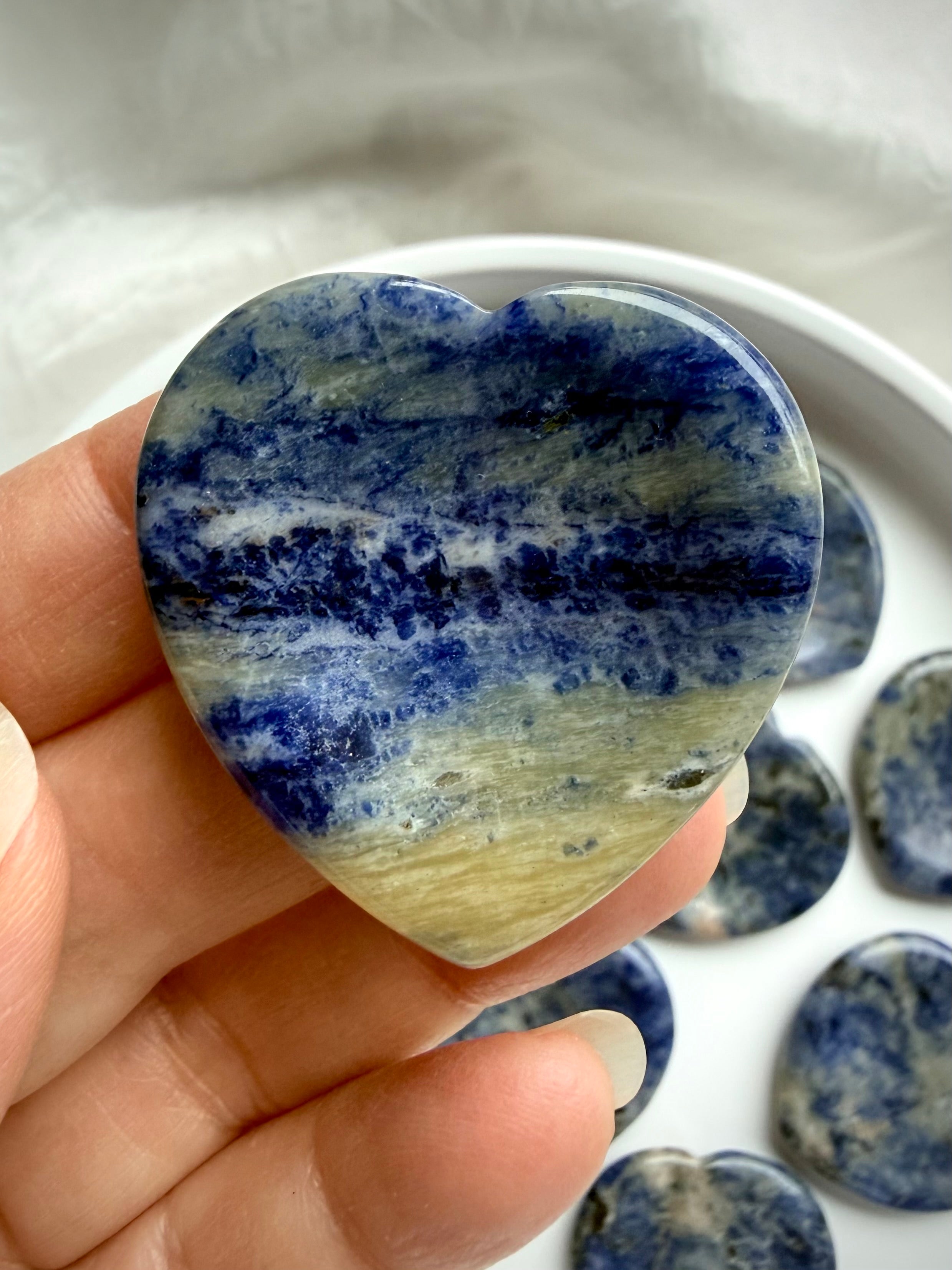 Sodalite heart worry stone held in hand showing blue and white natural stone patterns