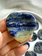 Sodalite heart worry stone held in hand showing blue and white natural stone patterns