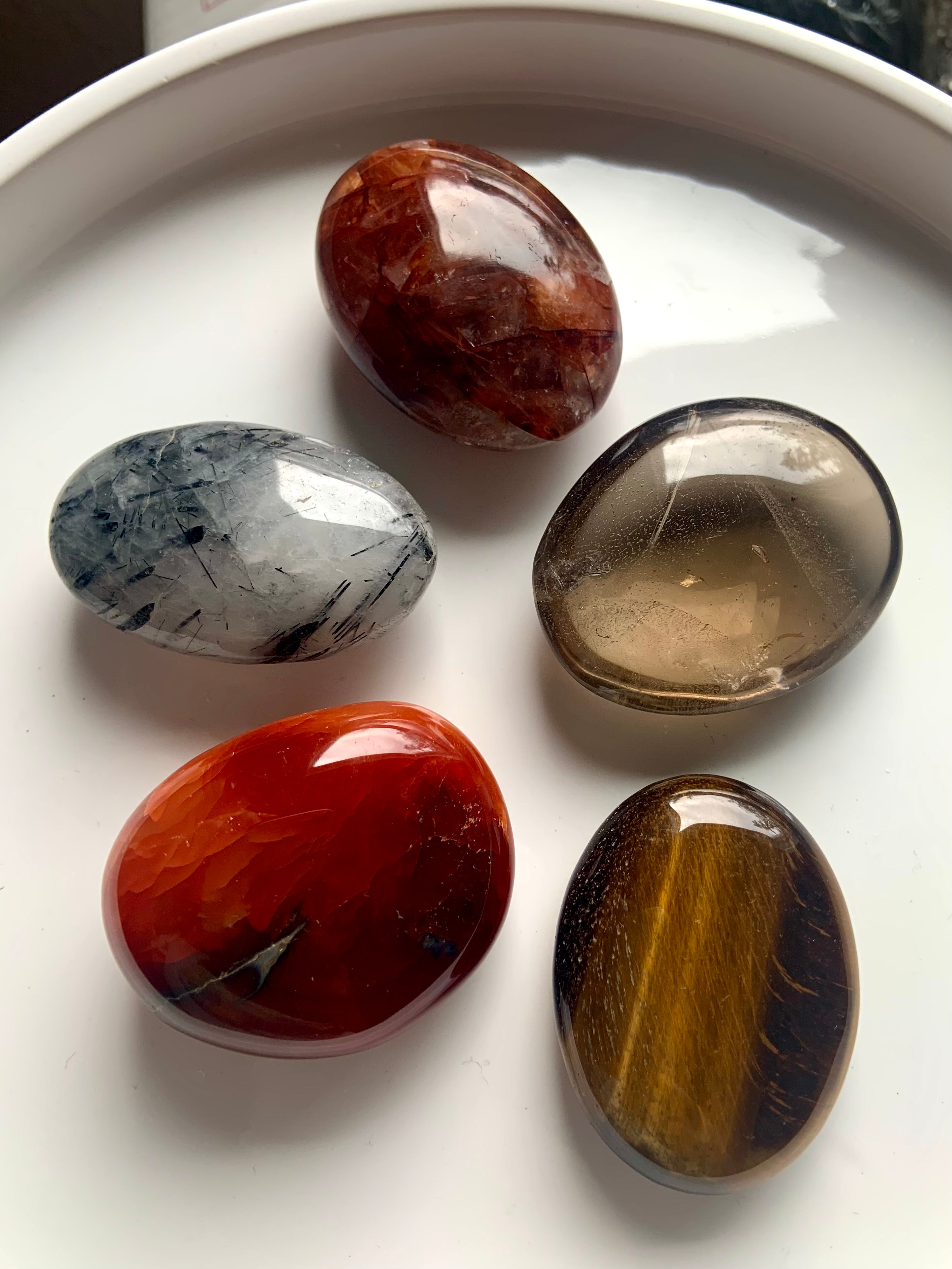 Polished palm stones on a white plate — crystal set for Root, Sacral &amp; Solar Plexus chakra healing, motivation &amp; energetic alignment.