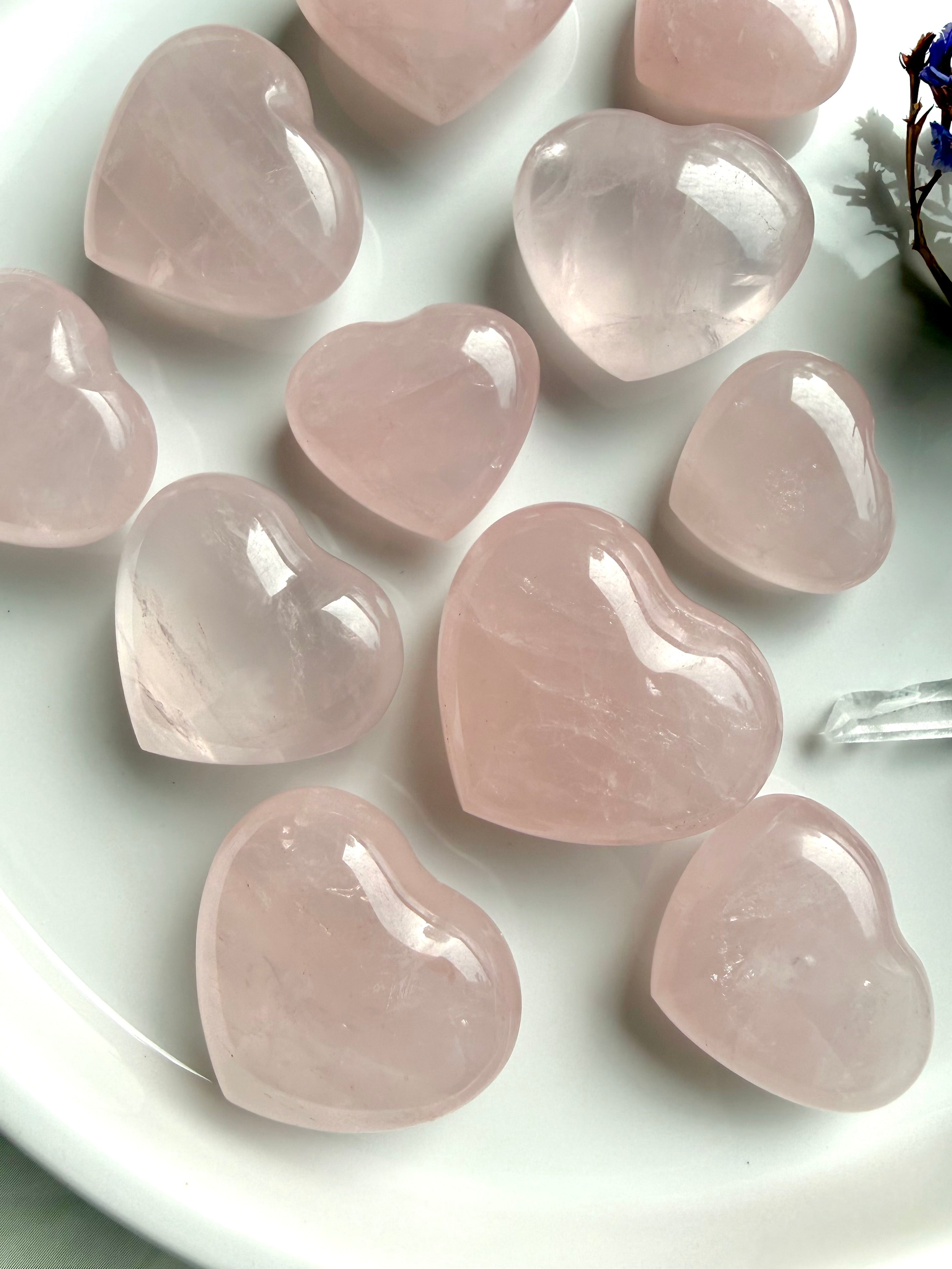 Natural rose quartz hearts collection showing variation in color and translucency, polished crystal hearts