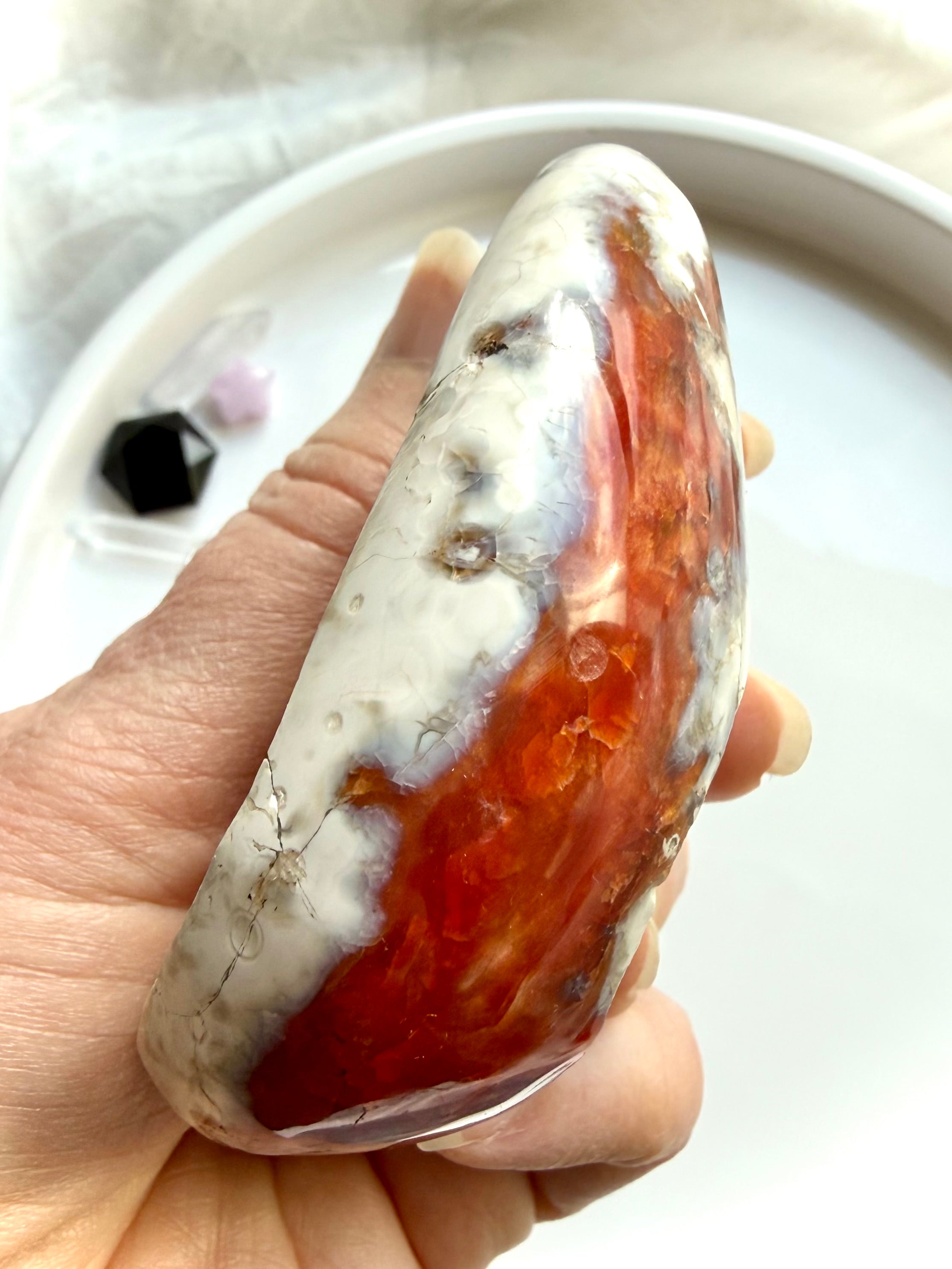 side view of polished carnelian bowl with orca agate pattern and translucent red orange tones