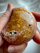 Peachy pink and yellow Ocean Jasper moon carving showing polished orbicular details and natural druzy accents