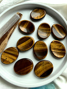 tiger’s eye oval worry stones arranged in ceramic dish, polished thumb stones for protection focus and personal power