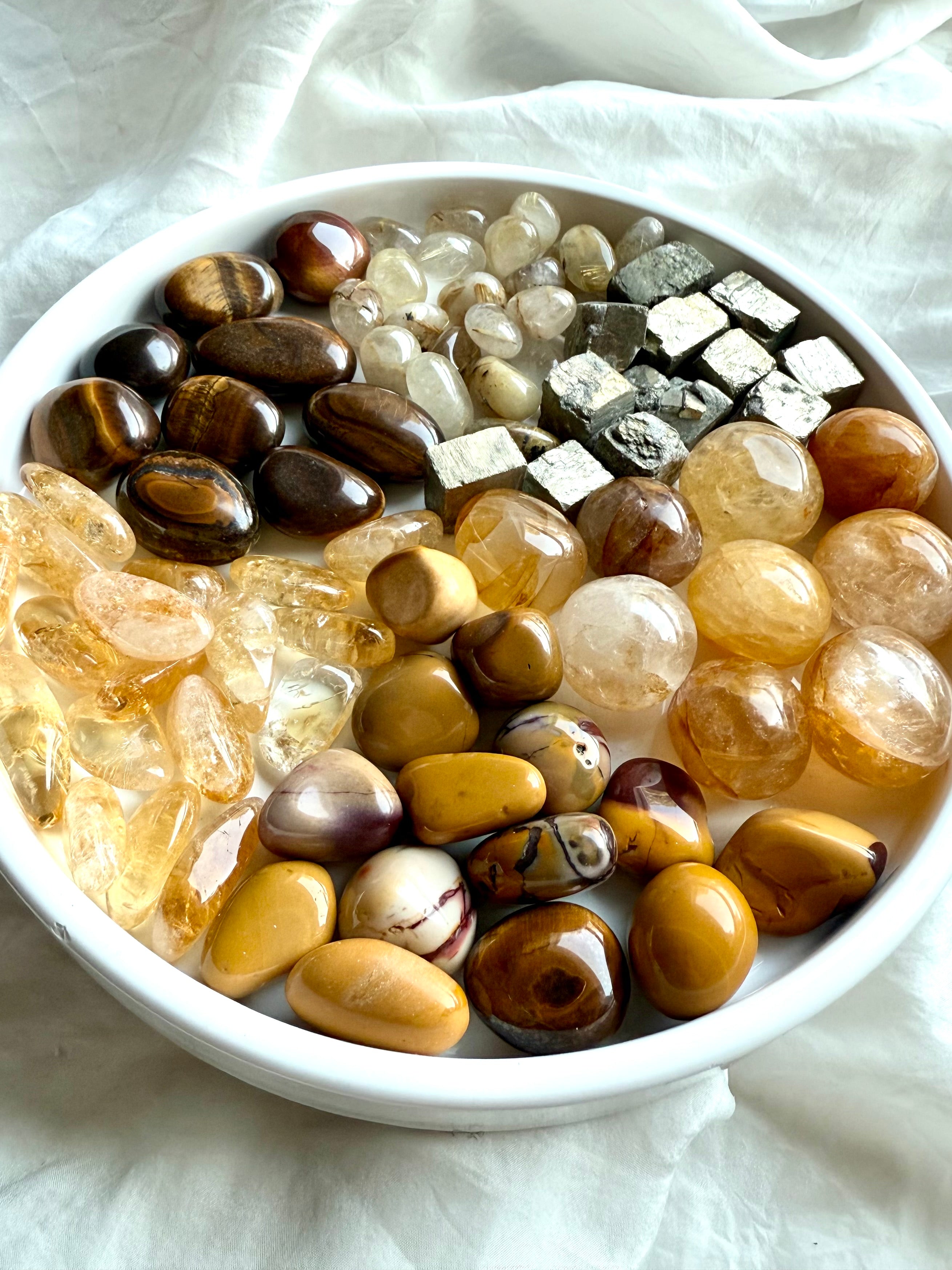 Solar Plexus Chakra crystal set with golden healer, citrine, golden rutile, tiger’s eye, yellow mookaite, and raw pyrite crystals glowing on a white plate