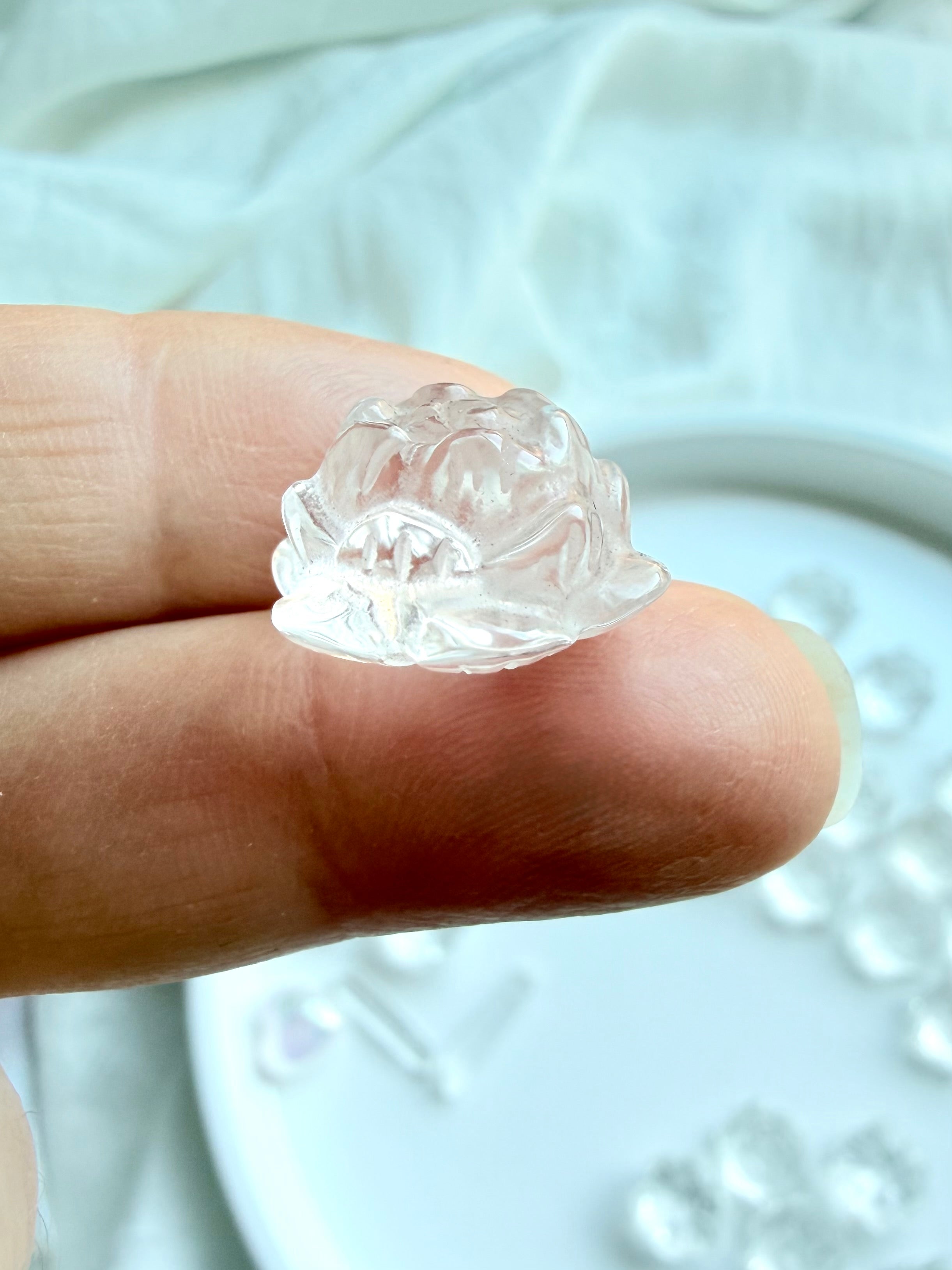 Tiny Clear Quartz lotus flower carving, side view shown on fingertip for scale, ideal as a pocket stone or crystal grid stone