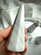 White and gray marble ring holder held in hand for size reference and stone pattern details