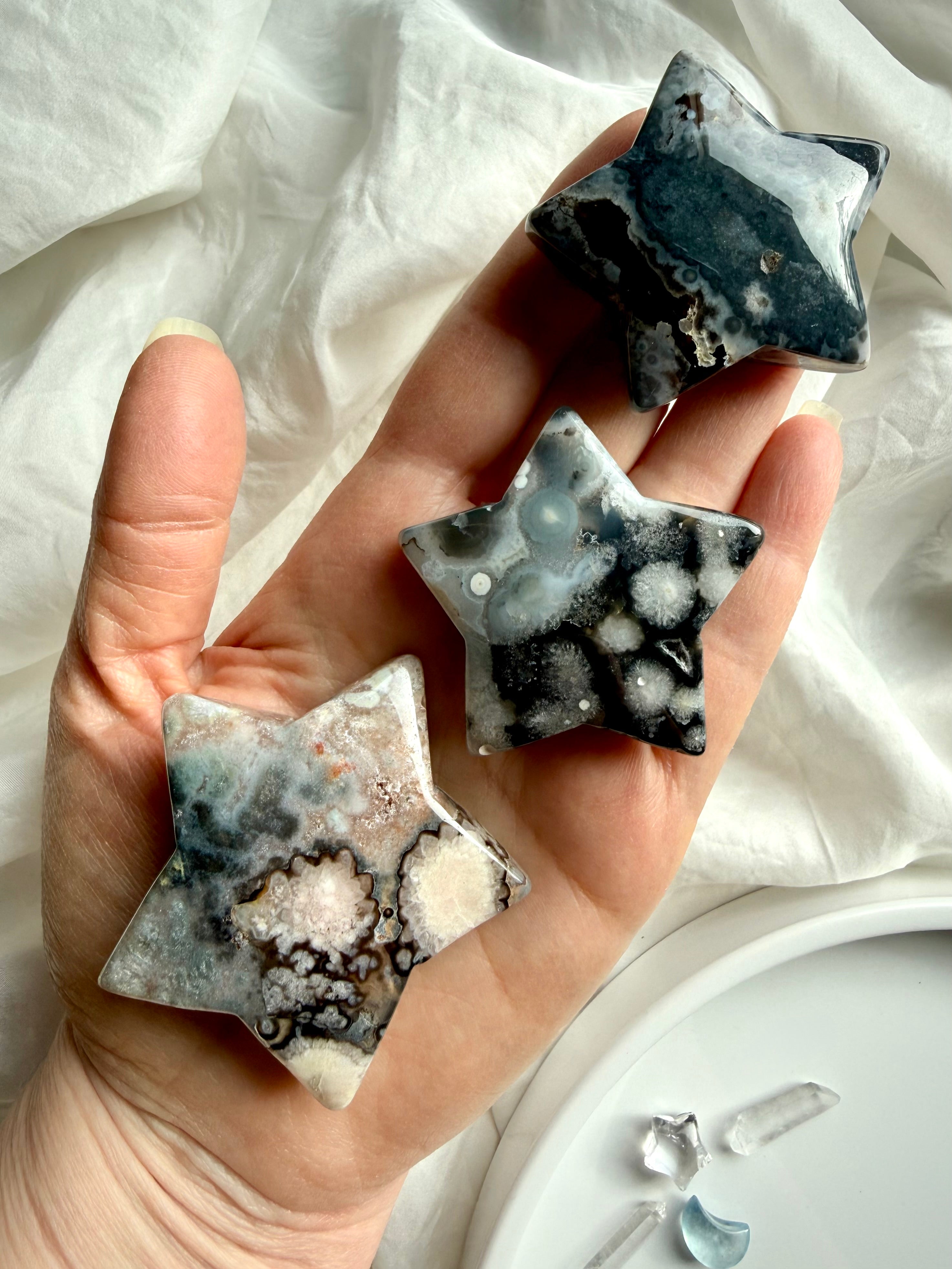 black flower agate moon and star carvings held in hand showing contrast of white blooms and dark agate base