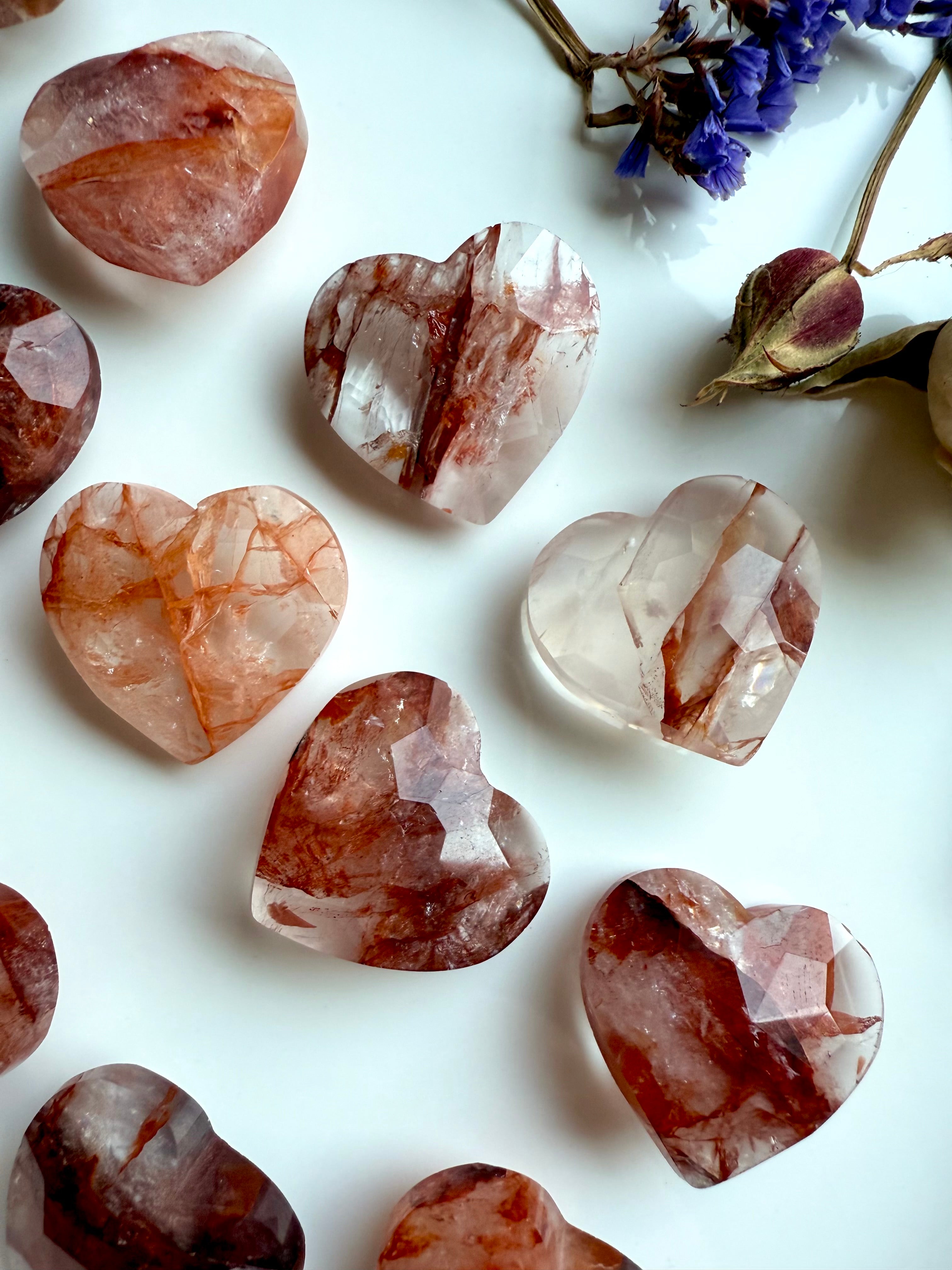 Closeup of Fire Quartz faceted heart carvings on white background – mini crystal for Root Chakra support
