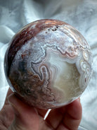 Banded agate sphere with soft purple and blush tones, featuring unique concentric ring formations