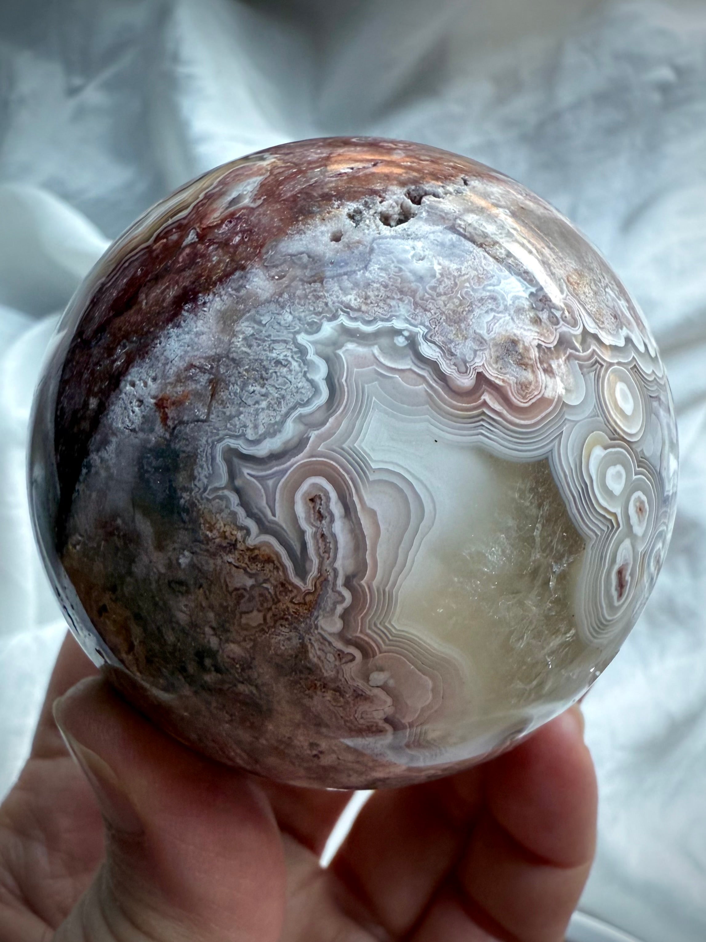 Banded agate sphere with soft purple and blush tones, featuring unique concentric ring formations