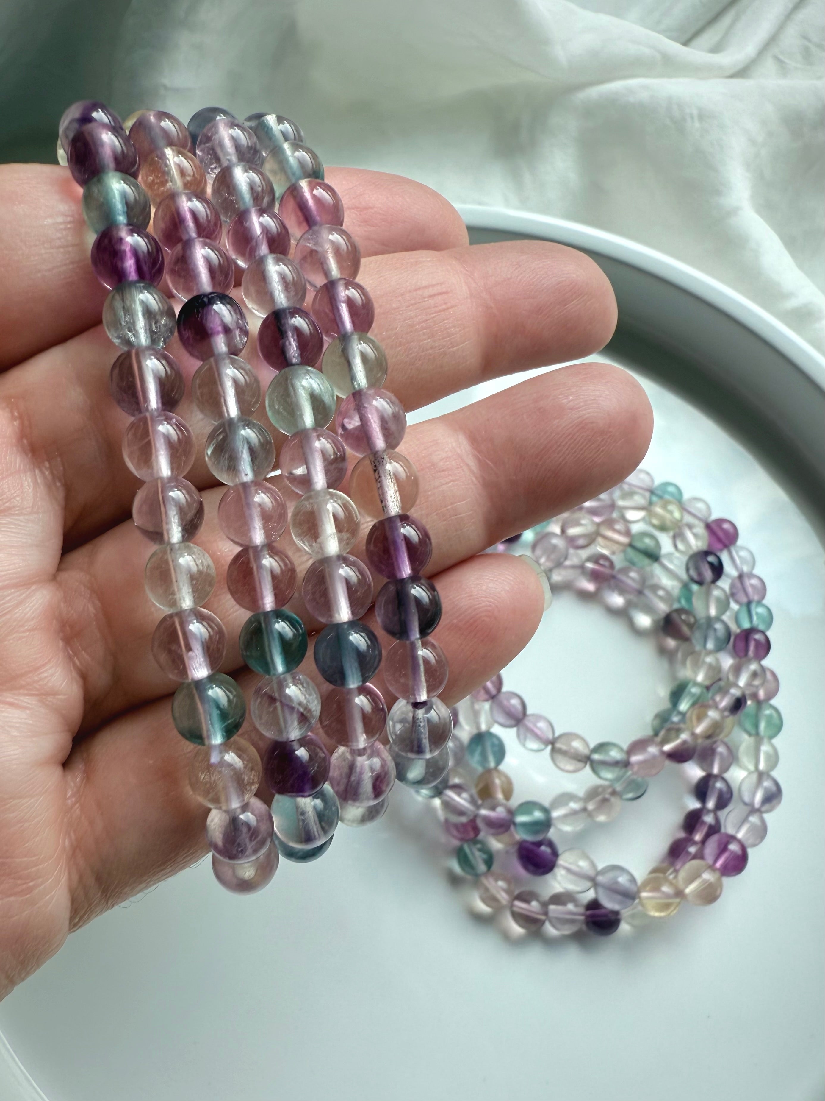 Fluorite bead bracelet shown on hand featuring polished translucent gemstones for focus & intuition