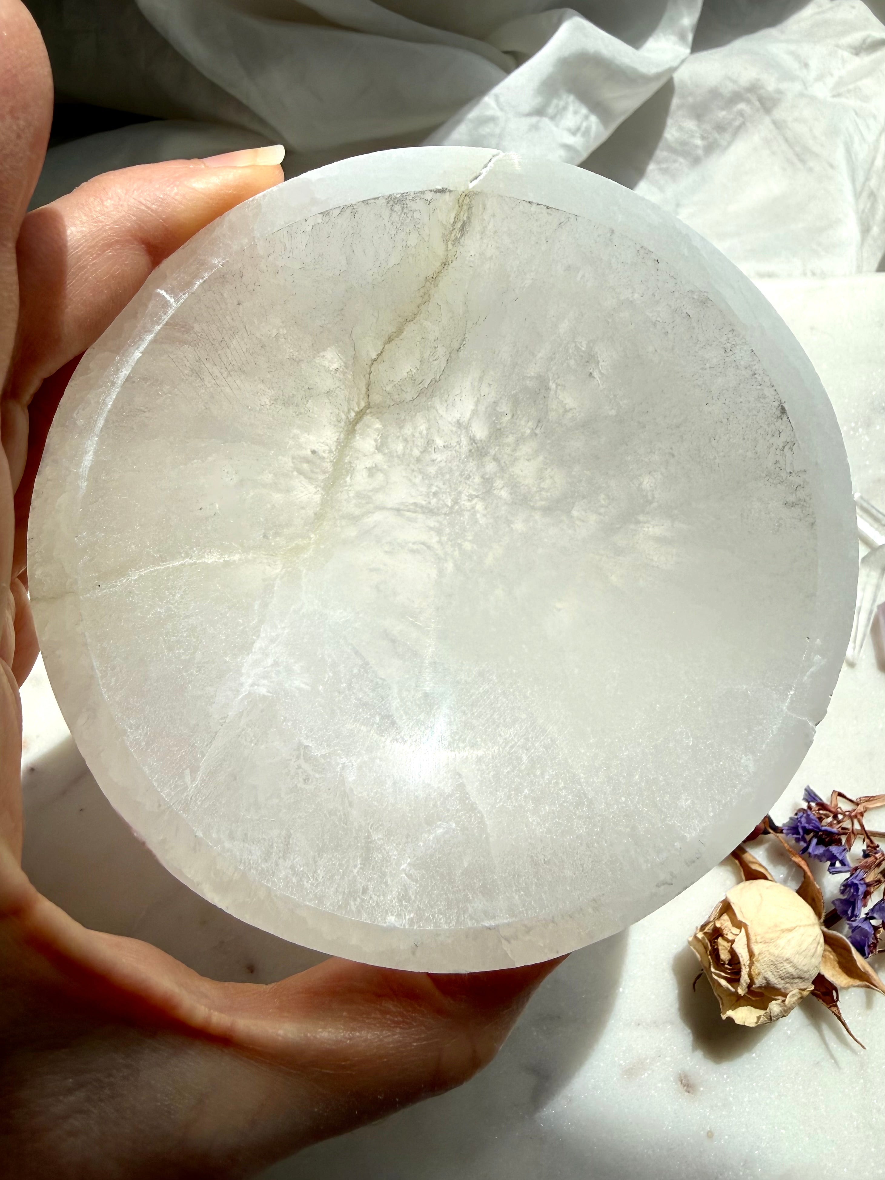 large selenite bowl in hand showing size and glow, natural crystal dish for energy clearing and display