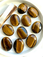 Collection of Tiger’s Eye palm stones displaying natural golden flash and silky bands of chatoyancy