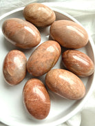 Polished Peach Moonstone palm stone with creamy peach tones and subtle feldspar shimmer