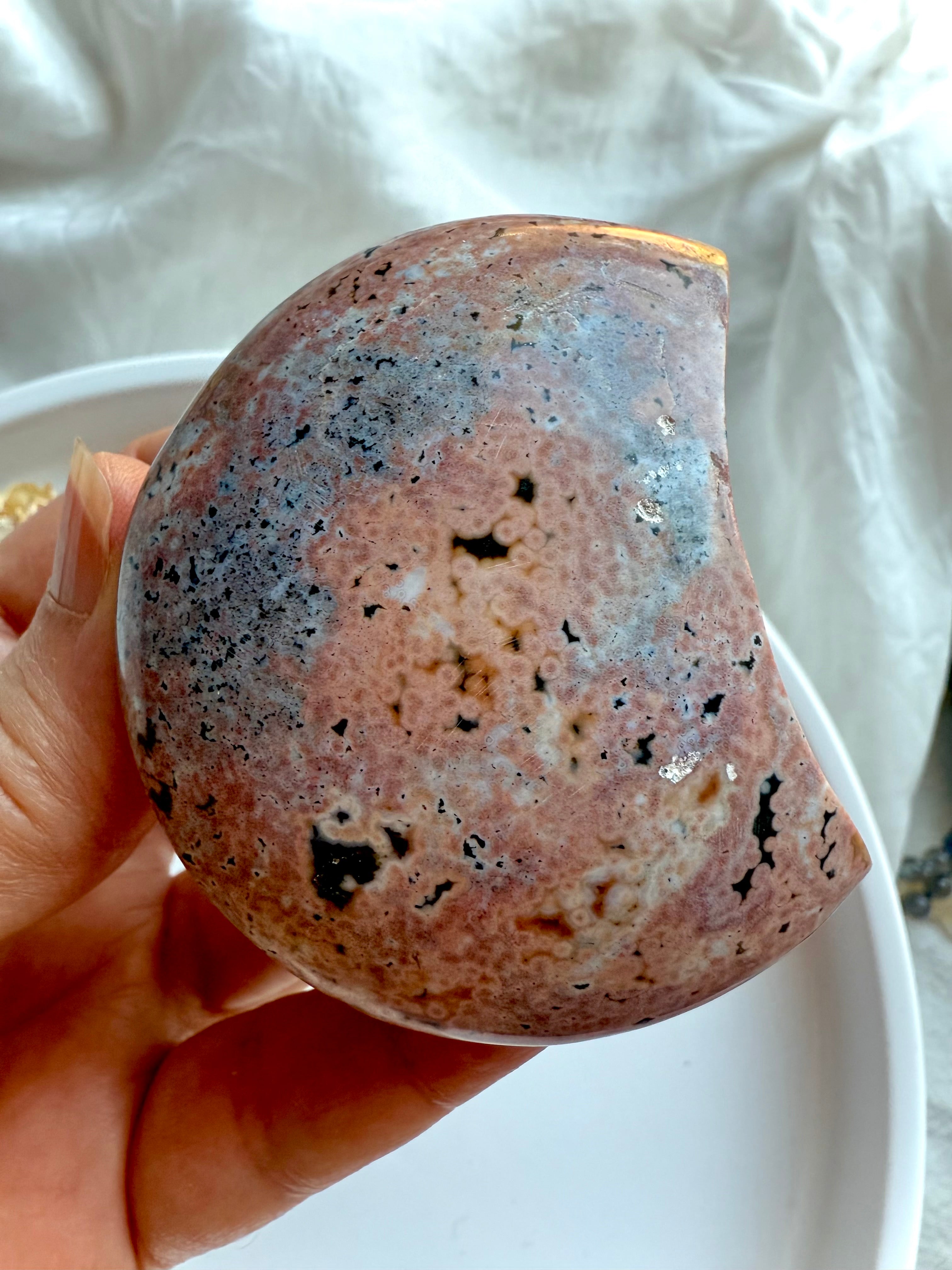 soft pink and grey ocean jasper moon with natural orbs and inclusions shown in hand, calming gemstone for emotional release and gentle grounding
