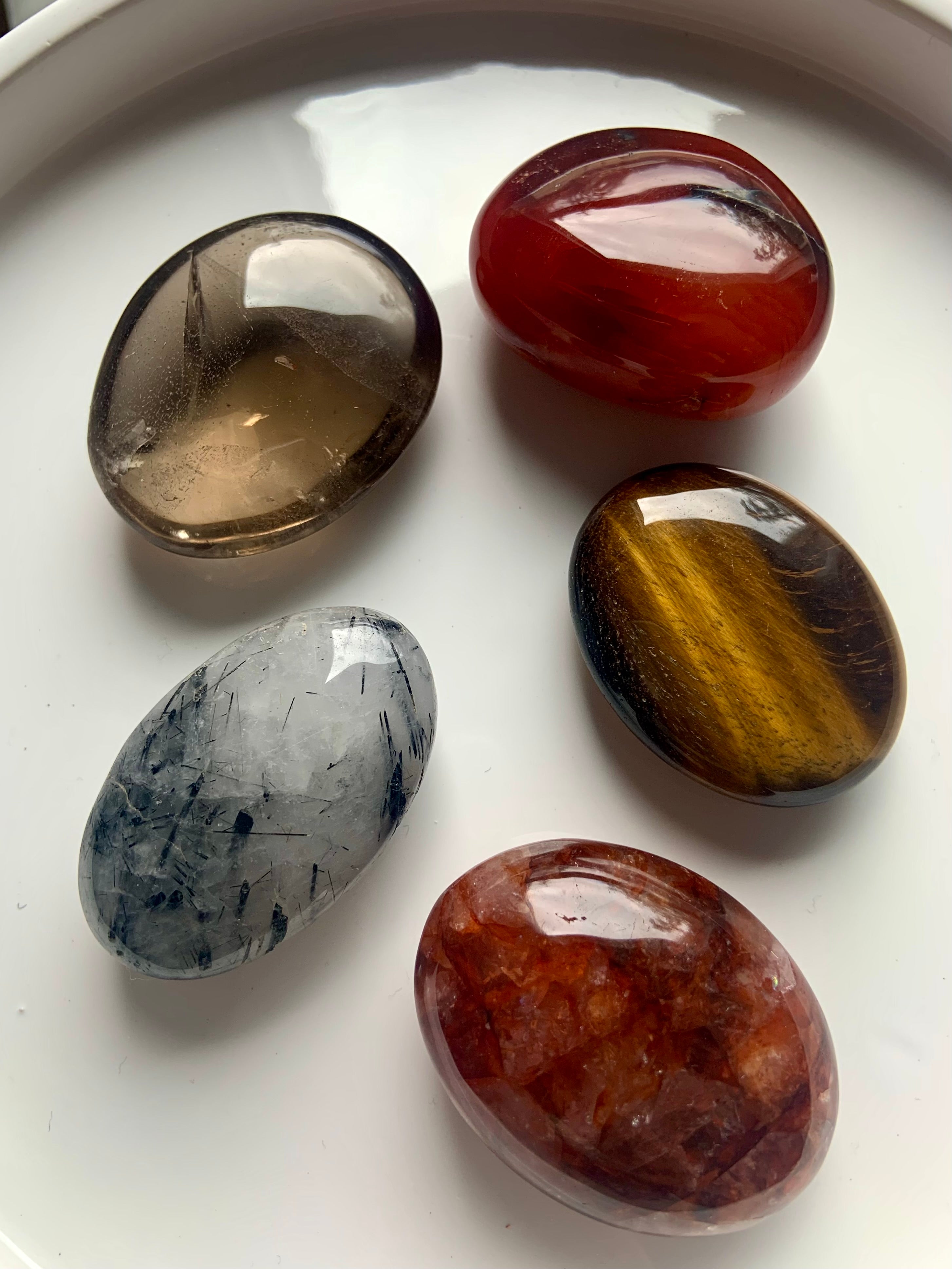 Root, Sacral + Solar Plexus Chakra crystal palm stone set on white plate — includes Smokey Quartz, Tigers Eye, Carnelian, Fire Quartz &amp; Tourmaline in Quartz.
