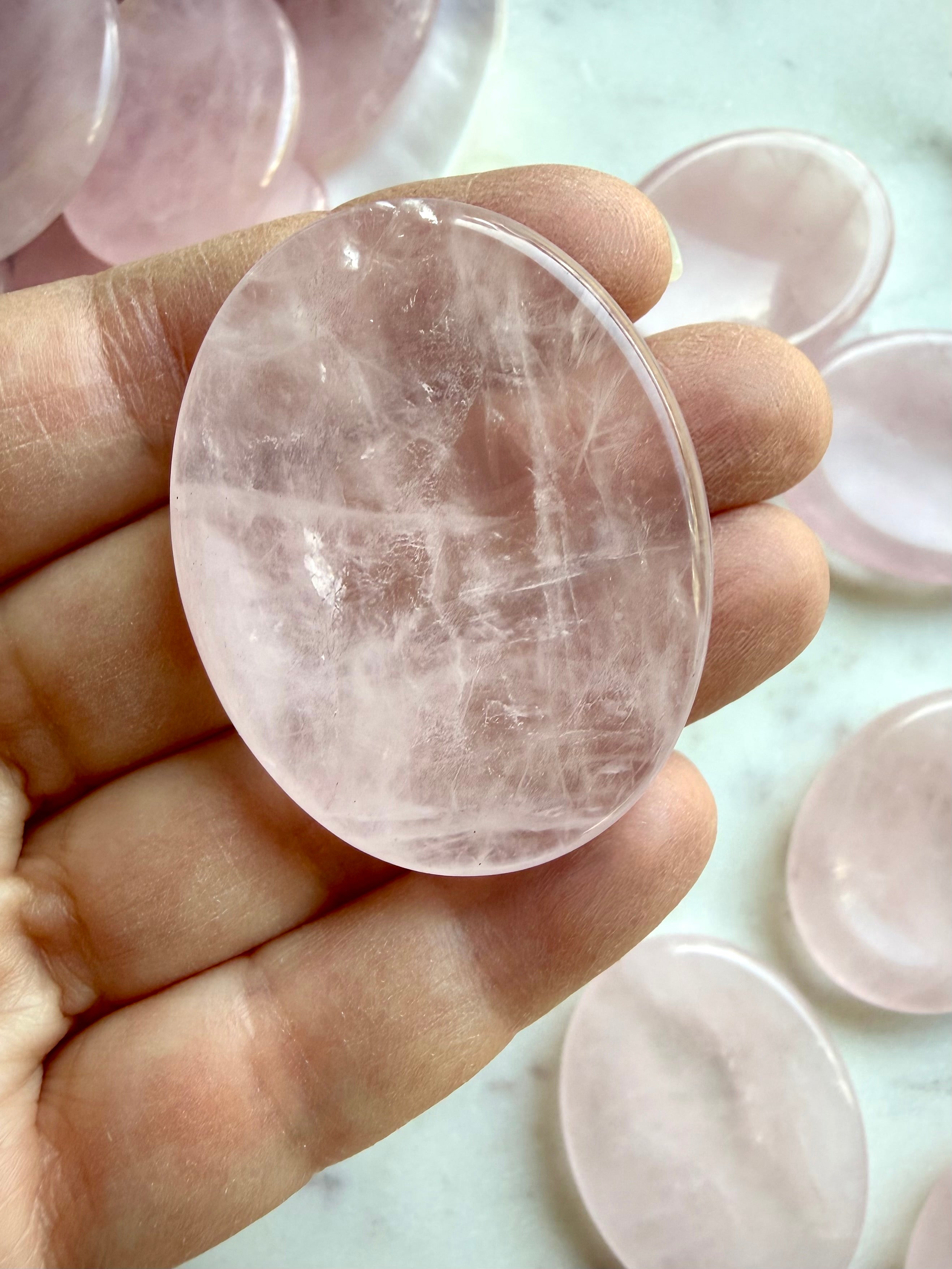 rose quartz palm stone held in hand for love compassion and emotional balance