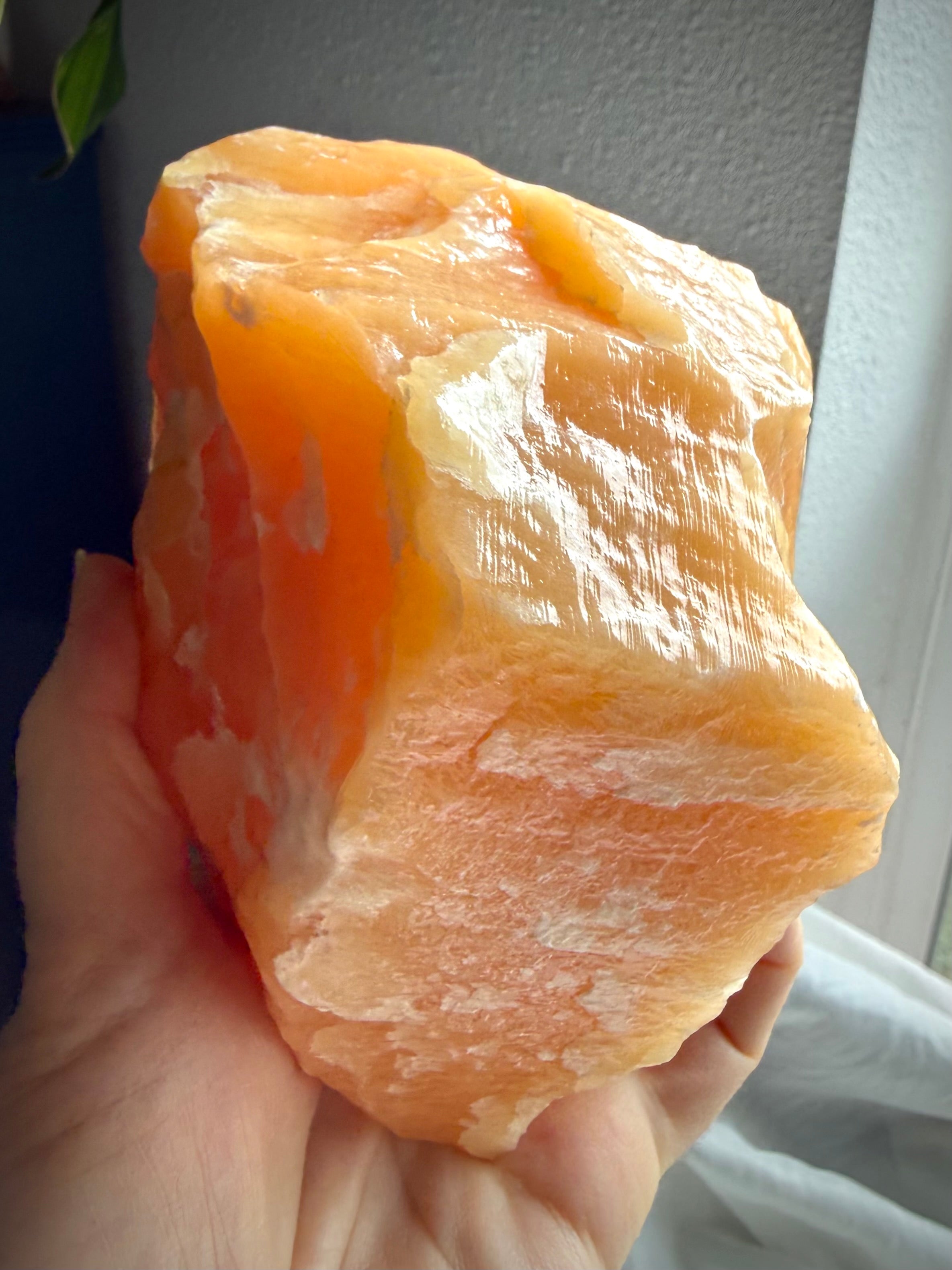 Orange Calcite display specimen illuminated by natural light with vibrant orange glow and mineral depth