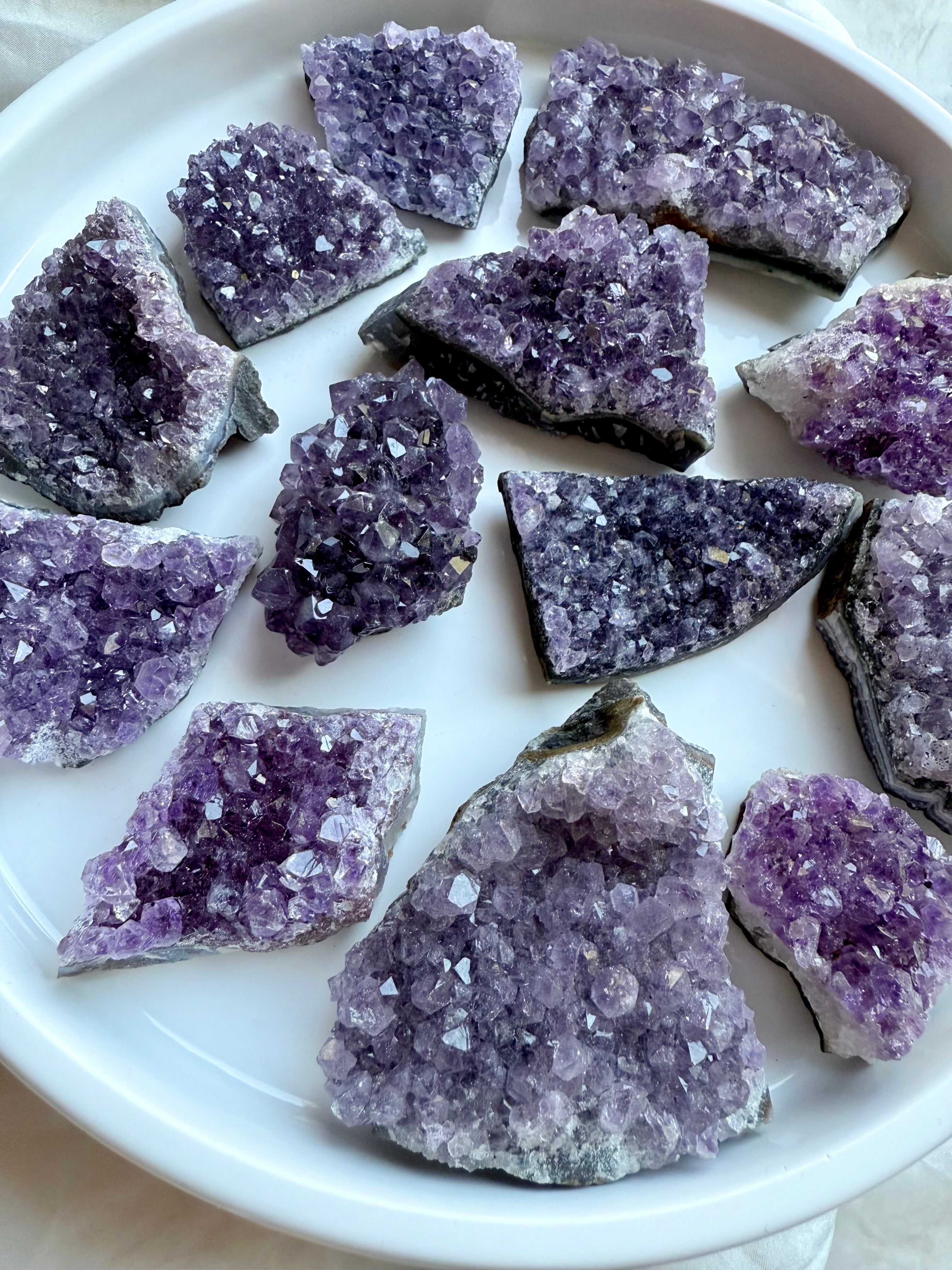Angled view of amethyst geode clusters on white, sparkling purple crystals. Crown Chakra Healing stones for peace & clarity.