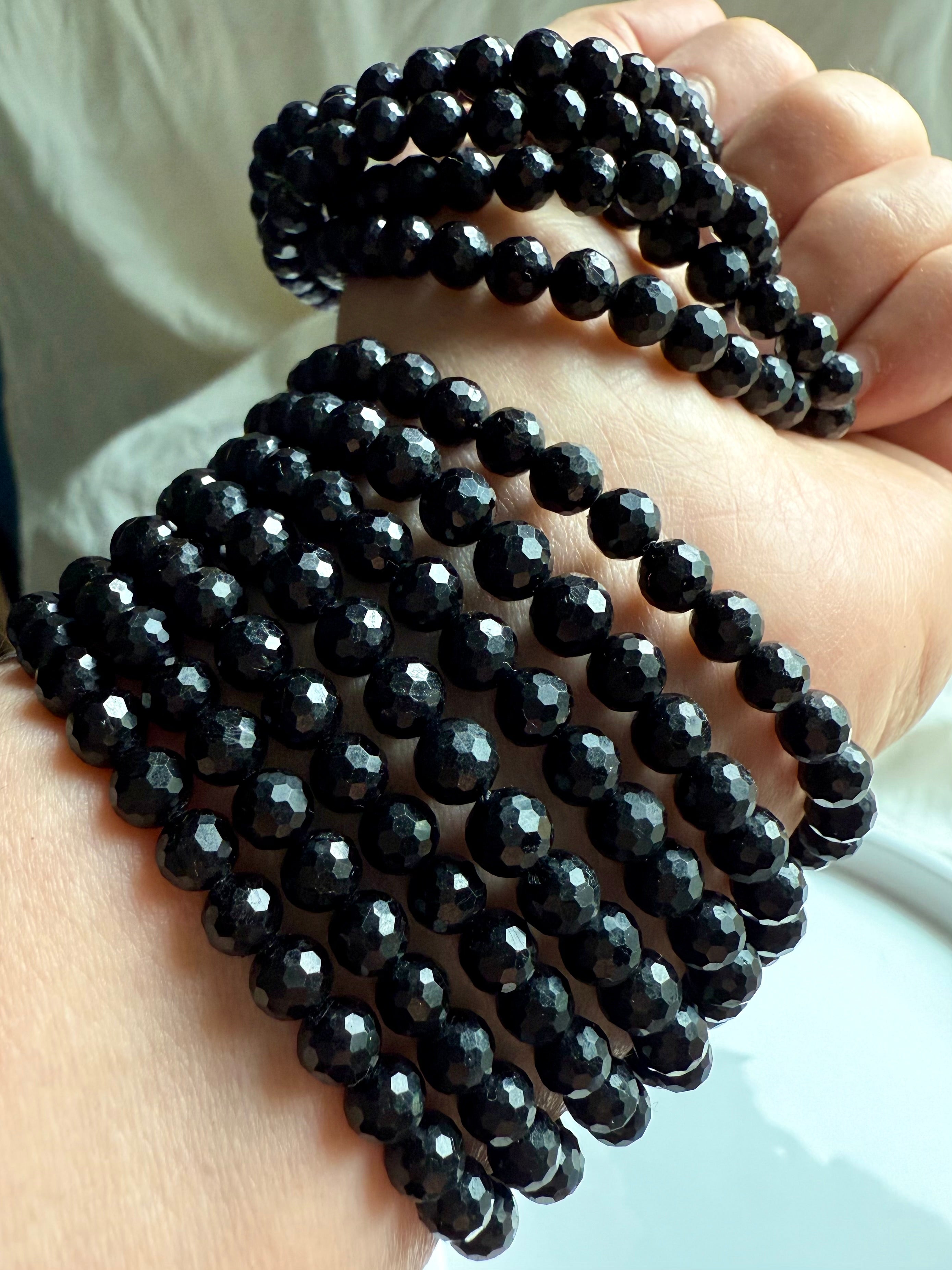 stack of faceted black tourmaline bracelets wrapped around wrist for layered energy protection and EMF shielding 
