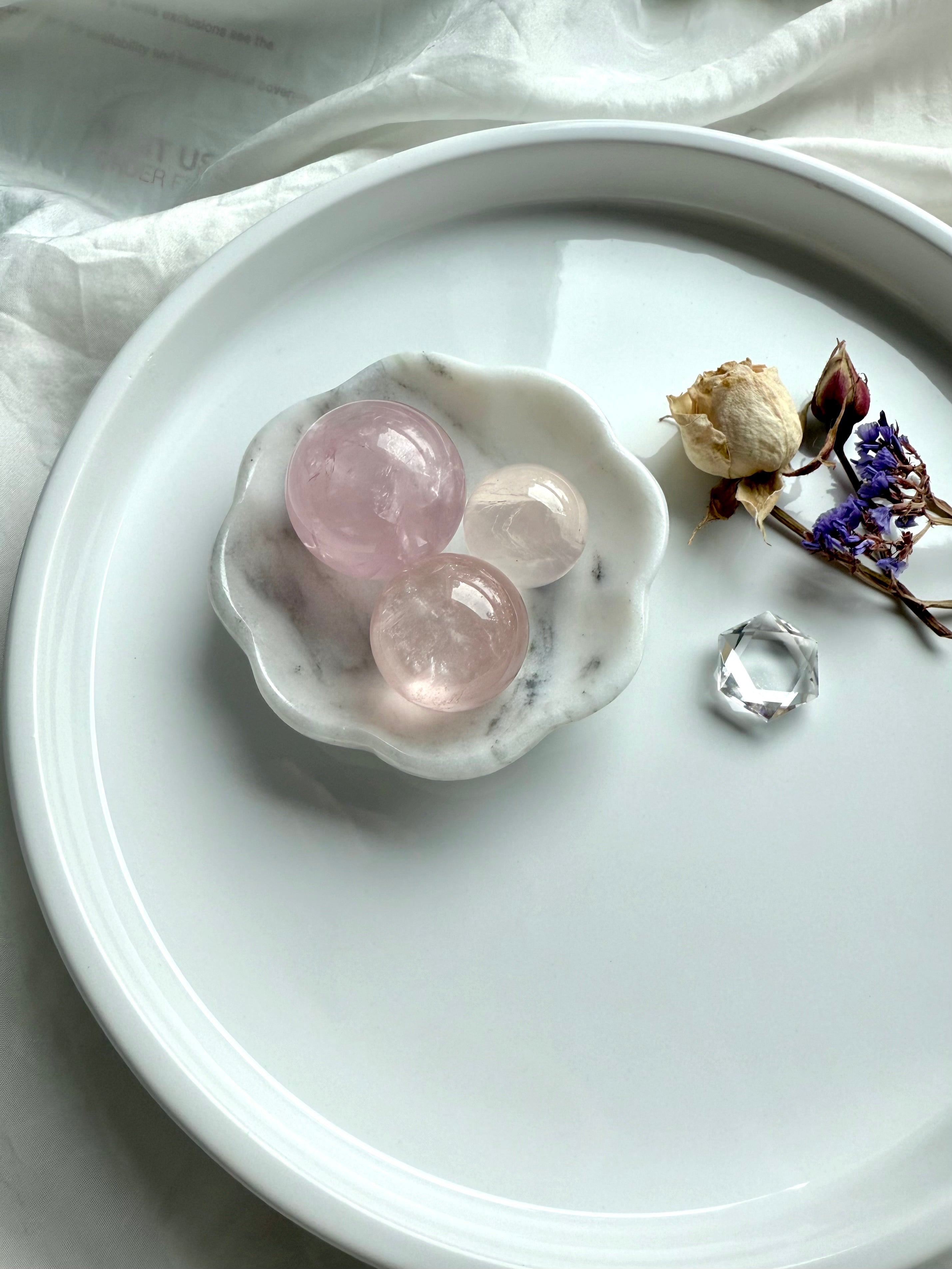 White marble daisy bowl styled as a sphere holder with three mini rose quartz spheres