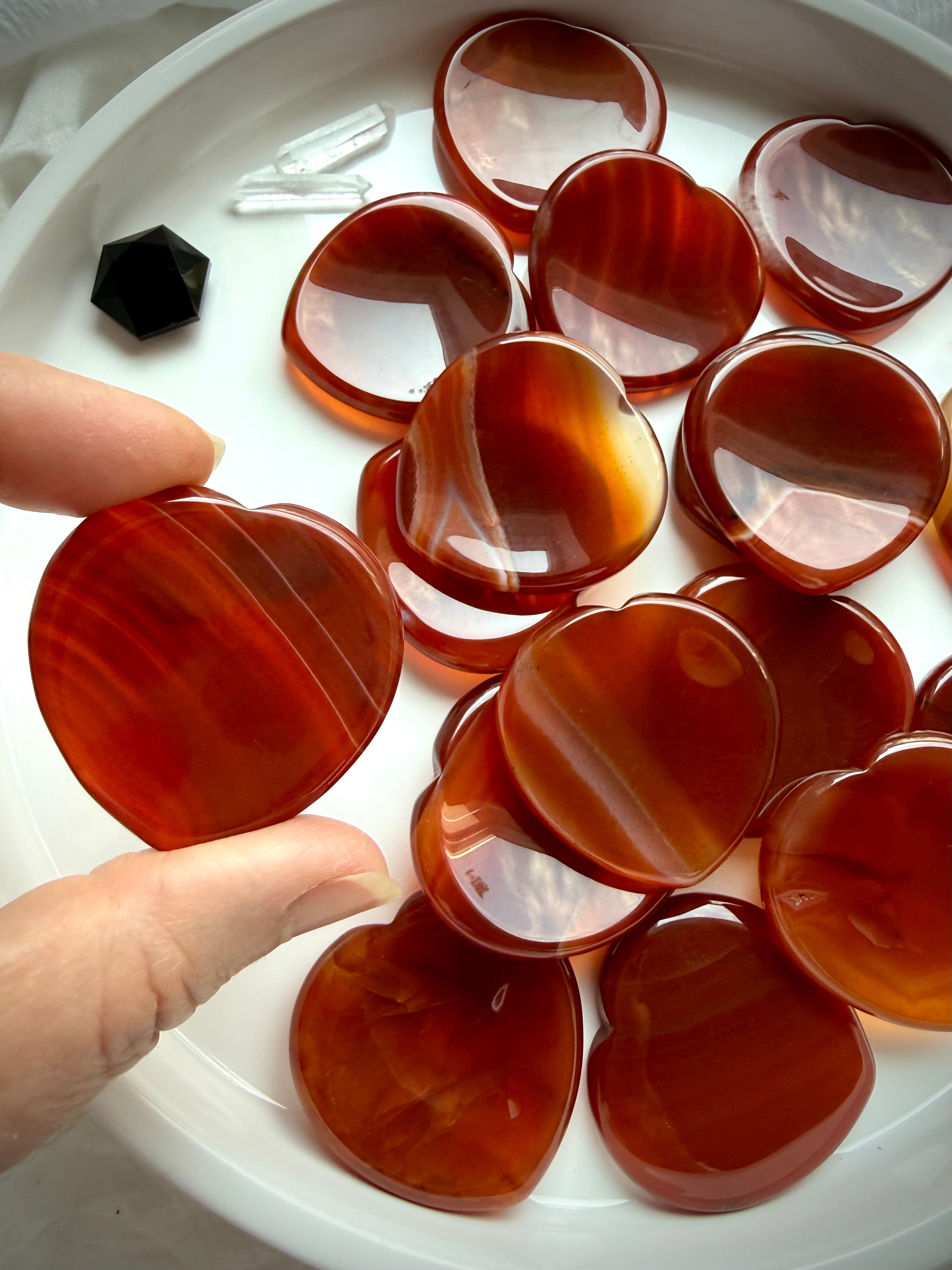 Carnelian heart worry stones showing glossy polish, translucent orange-red color and unique natural patterns