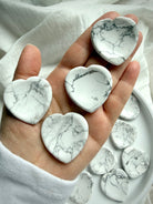 Howlite heart worry stones in hand showing natural white stone with gray marbling