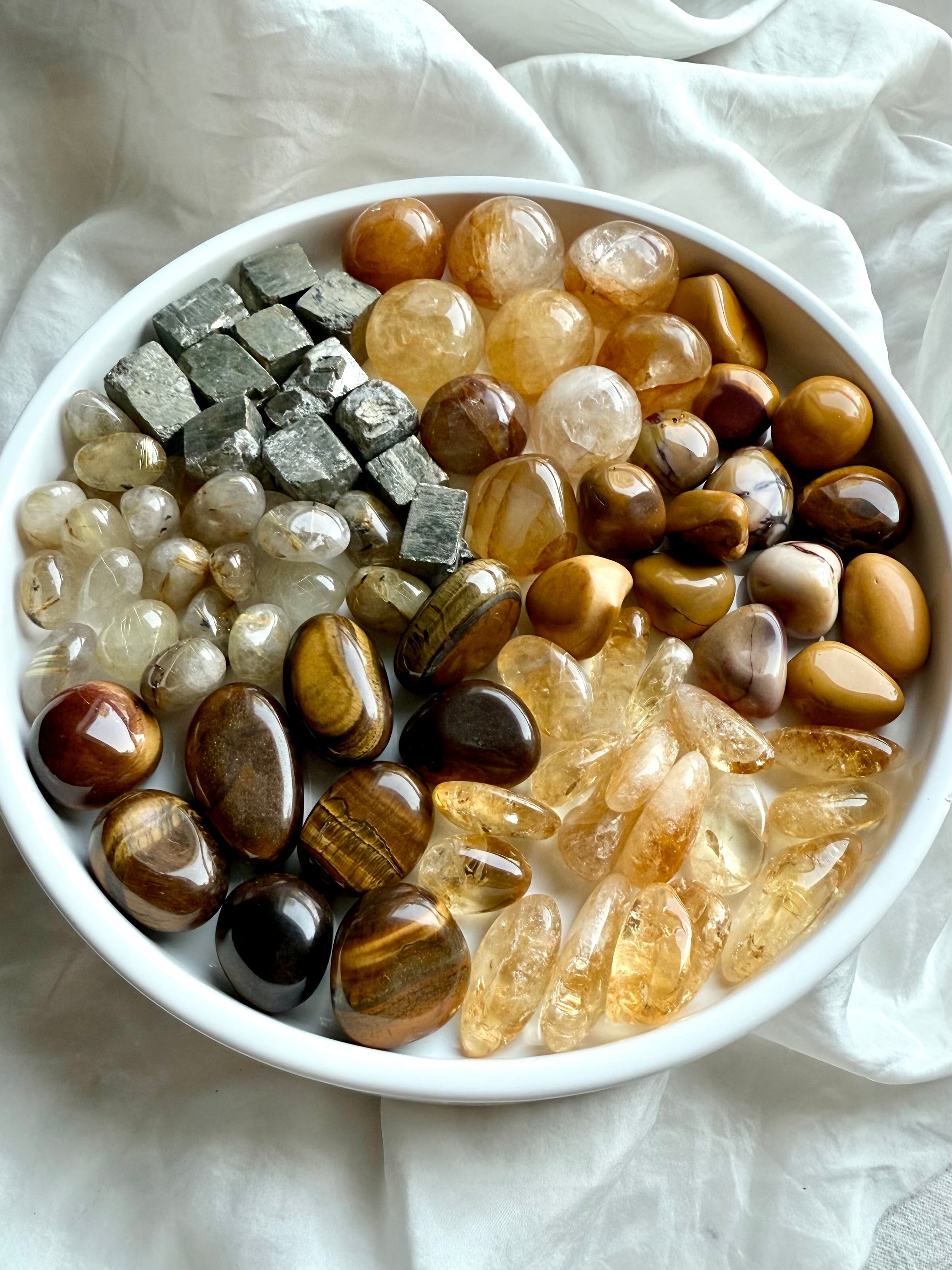 Wide view of chakra crystal set in pie-slice formation — solar plexus stones including golden healer, citrine, rutile, tiger’s eye, mookaite, and raw pyrite on white plate