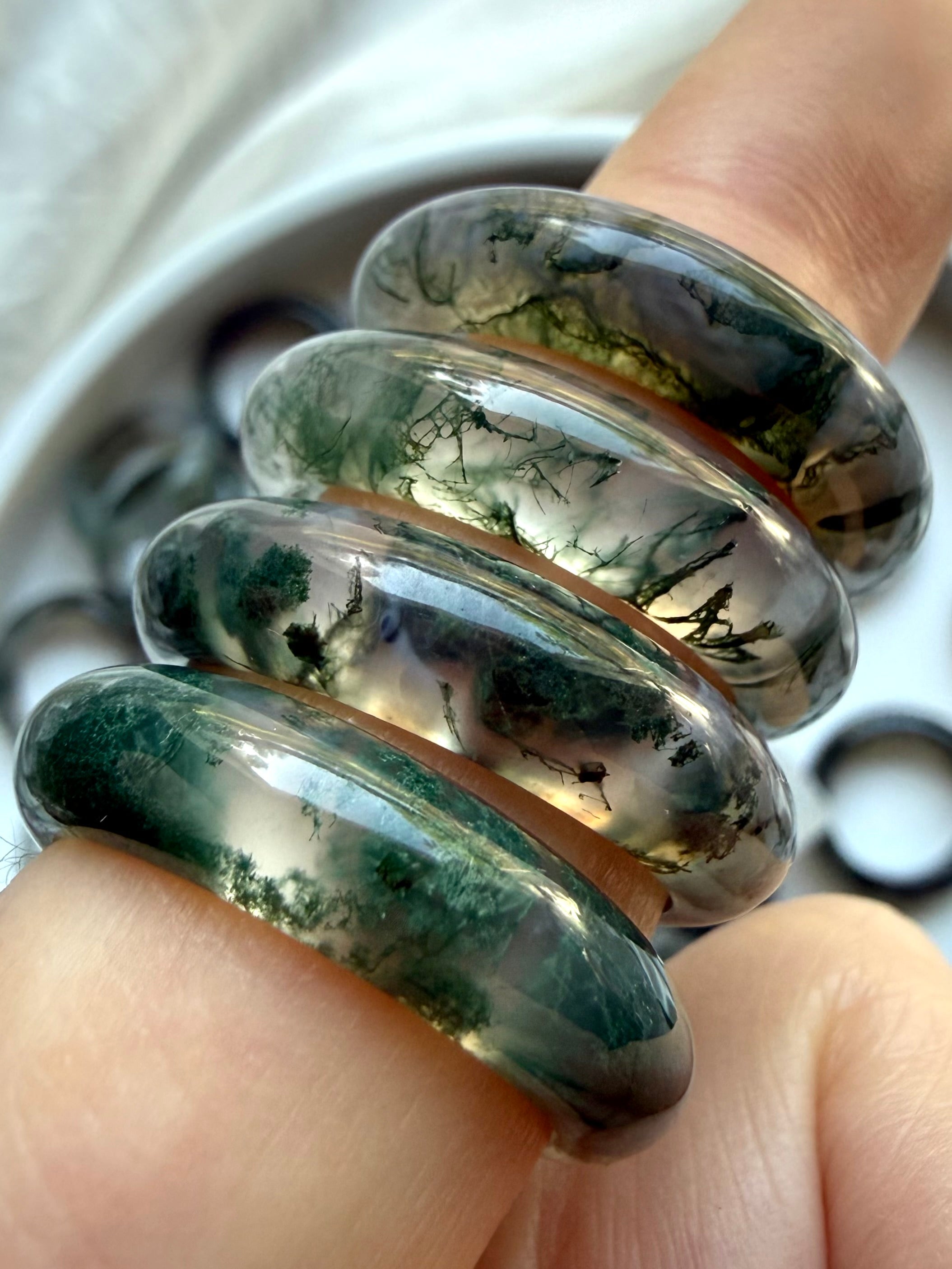 moss agate rings stacked on finger with visible green dendrites, grounding crystal jewelry for emotional balance and heart chakra energy