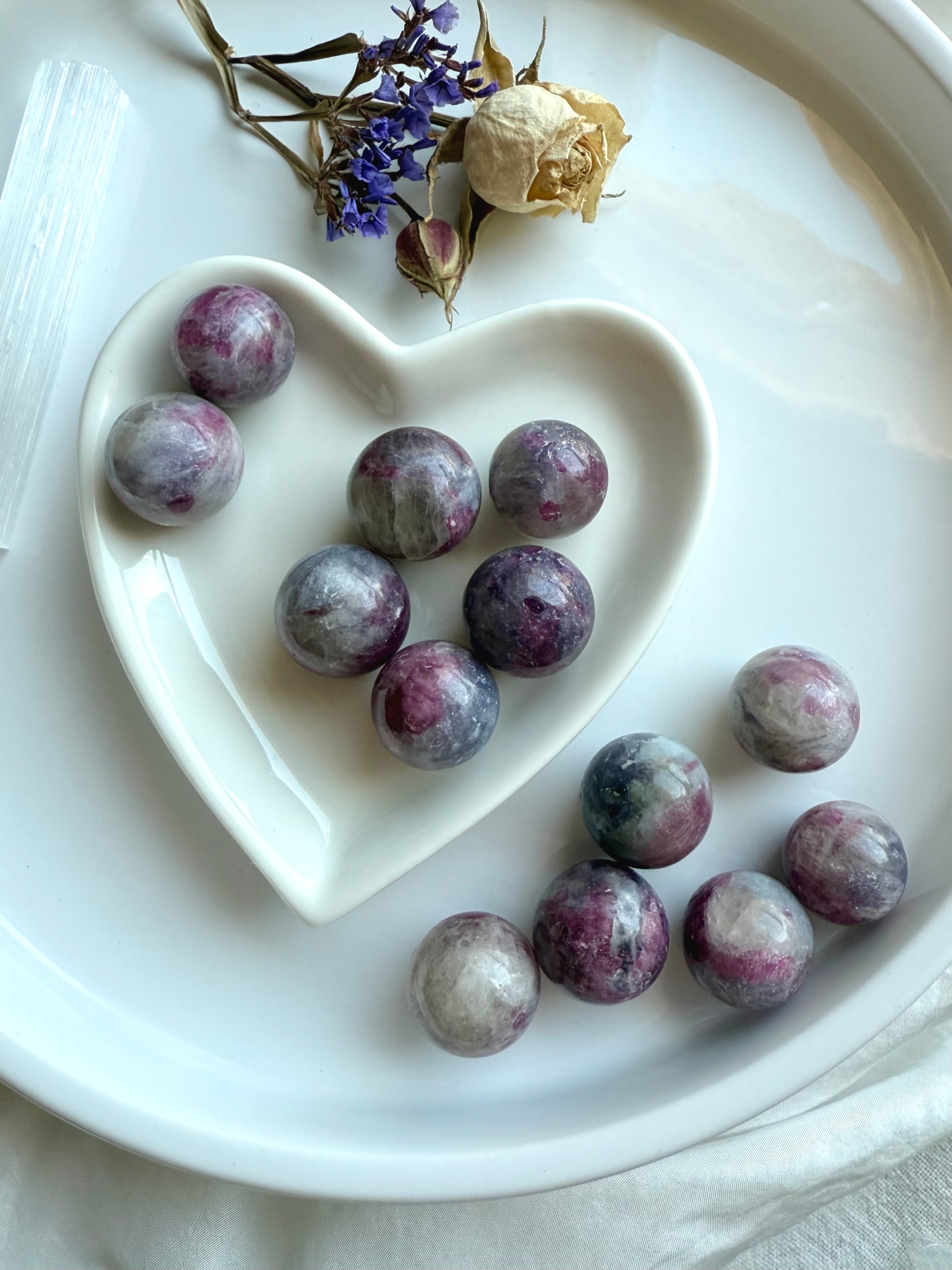 Heart-shaped dish filled with Unicorn Stone spheres surrounded by dried flowers for a calming display
