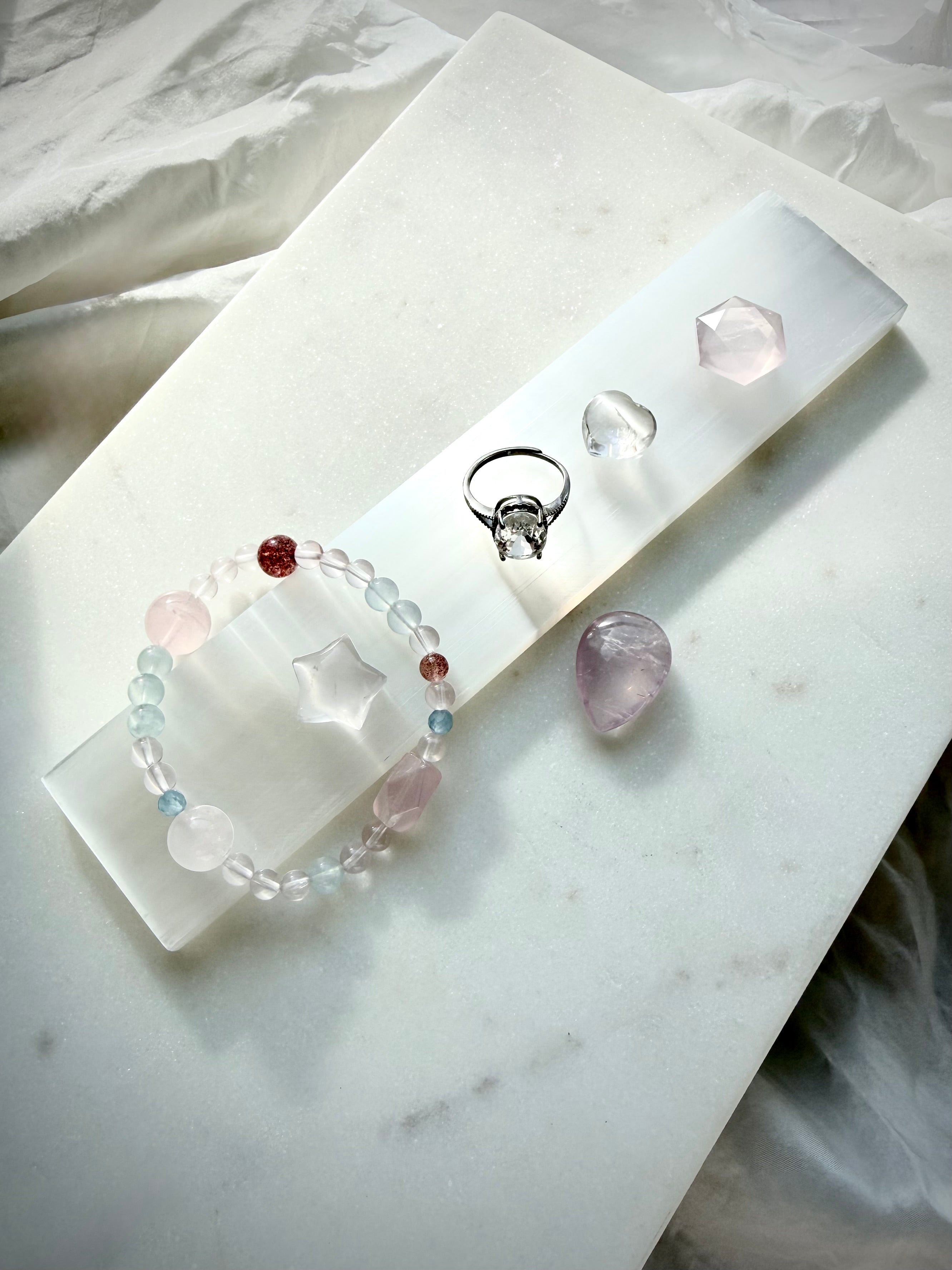 White Selenite charging wand displayed with small crystals and jewelry for crystal cleansing, charging and energy purification rituals